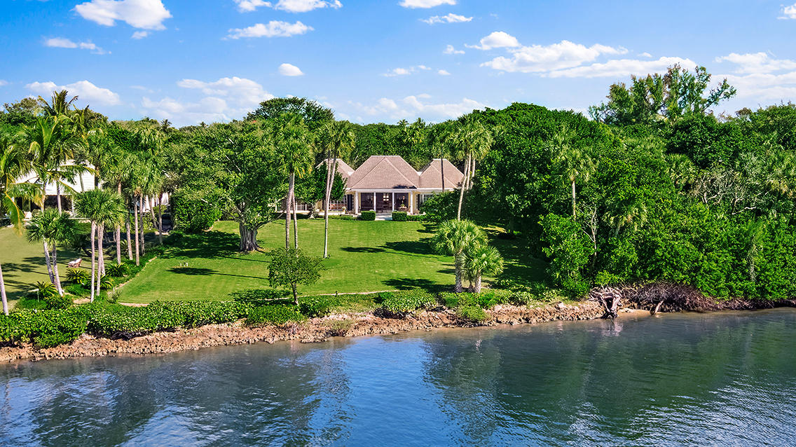 Enter down a long private drive to this beautiful Jupiter Island 2.9 acre Intracoastal property with wide water, undisturbed views across to a natural sanctuary. There is deeded ocean access directly across the street to a secluded pristine beach. The 4361 sq ft main includes 3 bedrooms and 5.5 baths. In addition, a 3 bedroom guest house each with its own bath plus a large living/dining area and full kitchen provides ample space for extended family and guests. Jupiter Island Building regulations allow for increased floor area to the existing structures or an additional building up to 13,414 sq ft. Room for a dock.