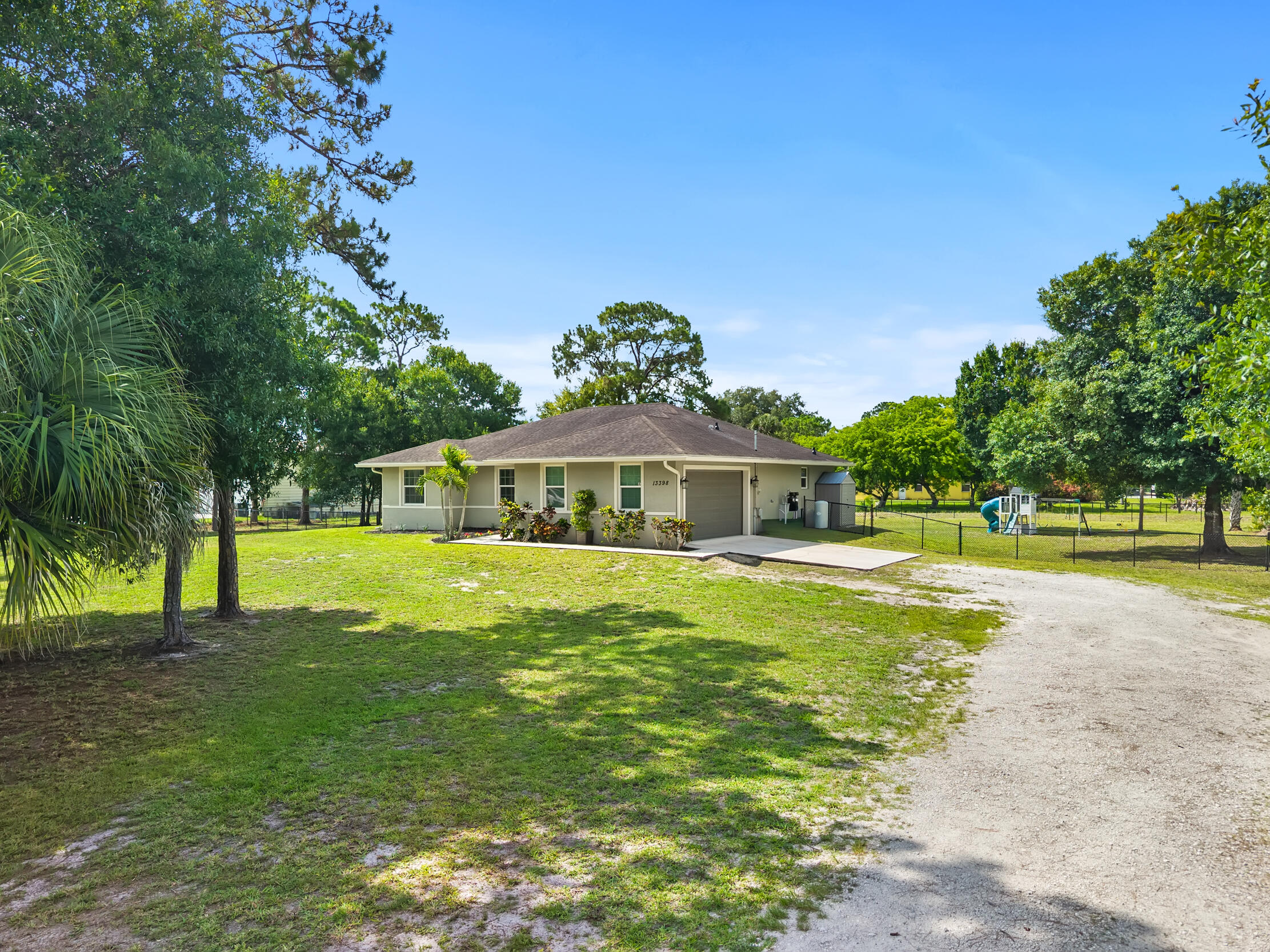 Welcome to this charming single-story 2017 Synergy built residence located in The Acreage. Featuring three bedrooms, two bathrooms, and a thoughtfully designed open living space, this split floor plan provides ample space for the entire family to live comfortably. With Wood look tile throughout the main living areas, a beautiful open dinning space right off the kitchen, upgraded cabinets with molding, custom light fixtures, Impact windows and doors, and a large island overlooking the living room, this home fits comfort and practicality. Sitting on 1.3 Acres of land you have the room and availability to add a mother in-law quarters, detached garage or workshop, and so much more.  Close to grocery stores, restaurants, and a short drive to the airport, there's not much this beautiful abode doesn't offer
