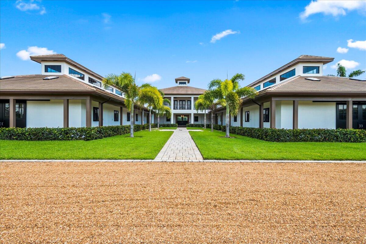 Luxury equestrian lifestyle beckons. This private gated farm is nestled in the the prime location of The Equestrian Club. Every feature of the custom built 18 stall barn reveals spectacular attention to detail. The barn has gorgeous cypress wood beamed ceilings with light filled cupolas and offers 2 aisles, each side mirroring the other. Thoughtfully constructed, both sides of this hurricane impact rated barn include new stall mats, an updated tack room, lounge/office with half bathroom, 2 wash stalls, 2 grooming stalls, a feed room, and a laundry room. Your horses will adore the brand new HSPG outdoor arena currently underway and 3 paddocks. The exquisite 3 bedroom, 3 bathroom owners residence is situated above the barn, is bathed in natural light, Beautifully appointed, the master suite has a huge custom built walk-in closet and a sleek en-suite bathroom with a soaking tub and separate shower.  An entertainer's dream, the open kitchen is well-equipped for all of your needs with state-of-the art Thermador Pro appliances, a 6 burner gas stove, wine fridge, a large island with prep sink and tons of storage space. Restore, relax, and enjoy outdoor living with access from each living space on the expansive covered patio with an outdoor kitchen and picturesque views overlooking the arena and paddocks. Other exterior amenities include an outdoor gas fire pit, a separate barn entrance for caretakers, a whole property security system, all surrounded by fully mature lush green landscaping and privacy hedging. Adjacent to the owner's home is an impressive 2 bedroom, 2 bathroom staff apartment that sits above an oversized 2 car garage with plenty of storage. The modern and bright apartment includes a full kitchen, laundry room, and balcony with equally enchanting views of the grounds. With an abundance of resort style community amenities, close proximity to WEF, dining and shops, you'll never want to leave this alluring equestrian oasis!