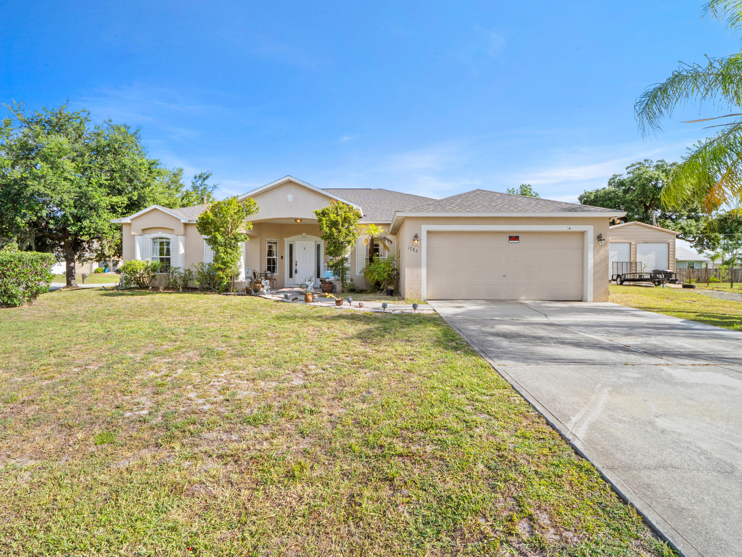 Welcome to this well-maintained 4-bedroom, 2-bath home in Palm Bay—no HOA! Built in 2005 and offering 2,252 sq. ft., this home sits on a generous .38-acre lot with a functional split floor plan and a 2-car garage. Major updates include a new roof and A/C (just 2 years old), giving peace of mind. Step outside to your screened-in lanai featuring a relaxing spa/hot tub, perfect for unwinding. A standout feature of the property is the impressive metal barn/workshop, built to 150-mph hurricane wind standards and featuring two overhead doors and RV electrical hookup, offering exceptional space for storage, hobbies, equipment, recreational vehicles, or additional workspace. An additional storage shed provides even more room for tools and toys.