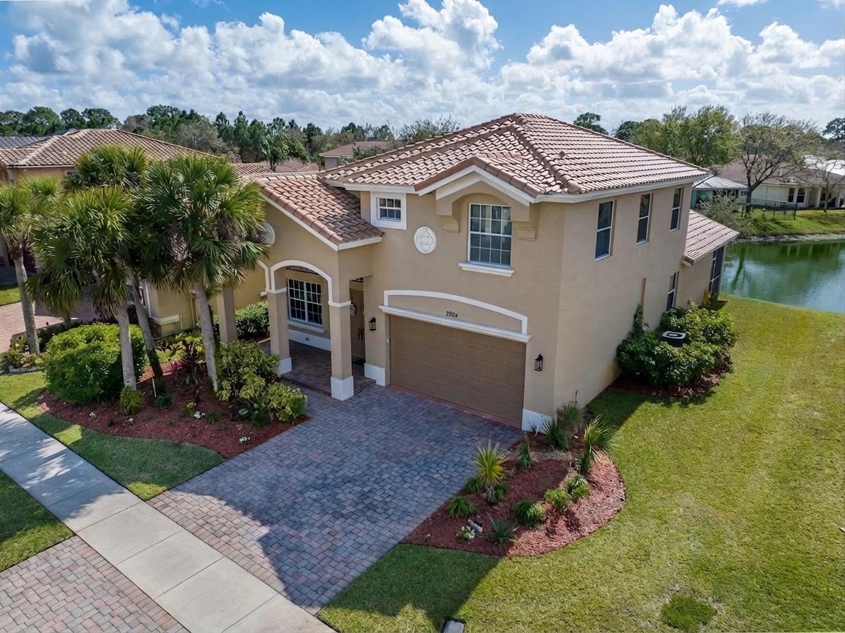 Beautifully maintained by seasonal owners, this spacious 4-bedroom, 2.5-bath home with a 2-car garage is located in a highly desirable, family-friendly gated community and offers stunning long lake views. As you enter, you are welcomed by a light and bright living room that provides a comfortable space for relaxing or entertaining guests. The large kitchen opens seamlessly to a generous family room, creating an inviting open-concept layout perfect for everyday living while enjoying picturesque water views. The primary suite is conveniently located on the main level, offering privacy and ease of living. Upstairs you will find three generously sized guest bedrooms, a full guest bath, and a large landing area that serves as an ideal flex space for a home office, media room, or play area.  Step outside to the covered, screened lanai where you can unwind while taking in the amazing long lake views, perfectly blending indoor and outdoor living. For ultimate peace of mind, protection & insurance discounts the home offers panel hurricane shutters for the entire home, new tile roof installed 2025 and A/C unit replaced in 2023. Residents enjoy low HOA dues that include internet, a manned security gate, common area maintenance, and access to outstanding community amenities including a clubhouse with fitness center, resort-style pool area, pickleball and tennis courts, and a playground. Conveniently located close to shopping, restaurants and easy 95 & turnpike access.