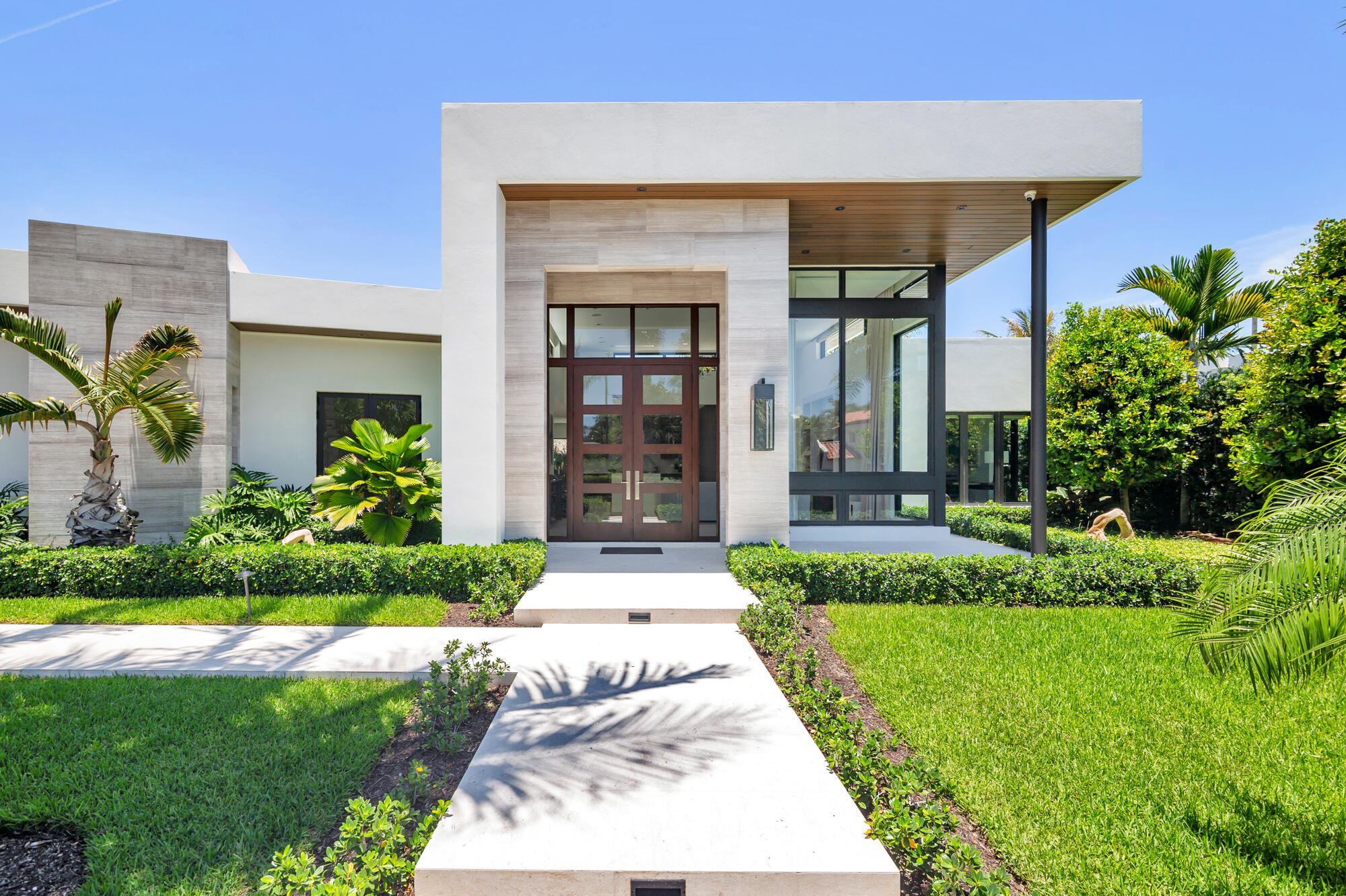 Offered for the first time, this exceptional 2023 custom-built estate showcases sophisticated one-story living with 5 bedrooms, 4 full baths, 1 powder bath, and 3,713 square feet under air (3,899 total square feet). Meticulously designed with no detail overlooked, the residence blends modern elegance with premium craftsmanship throughout. Soaring ceilings, designer finishes, motorized window treatments, and thoughtfully curated materials create a refined yet comfortable living environment. The stunning chef's kitchen is appointed with exquisite Naturali Calacatta Michelangelo Lucidato polished porcelain countertops, which are also featured in the primary bath and powder room. Beautiful Caliza Capri polished limestone flooring flows throughout the home, enhancing the bright, contemporary  aesthetic. Indoor and outdoor living seamlessly converge with a spectacular 475-square-foot covered tiki-hut entertaining area overlooking the heated saltwater pool—an ideal setting for year-round relaxation and entertaining. Additional features include a Kohler 48KW whole-house generator, providing peace of mind and uninterrupted comfort. Ideally located near area beaches, the Flagler Drive waterfront bike trail, acclaimed dining destinations, world-class shopping on Worth Avenue, and the pristine shoreline of the Atlantic Ocean, this extraordinary residence offers a rare opportunity to enjoy luxury coastal living at its finest.