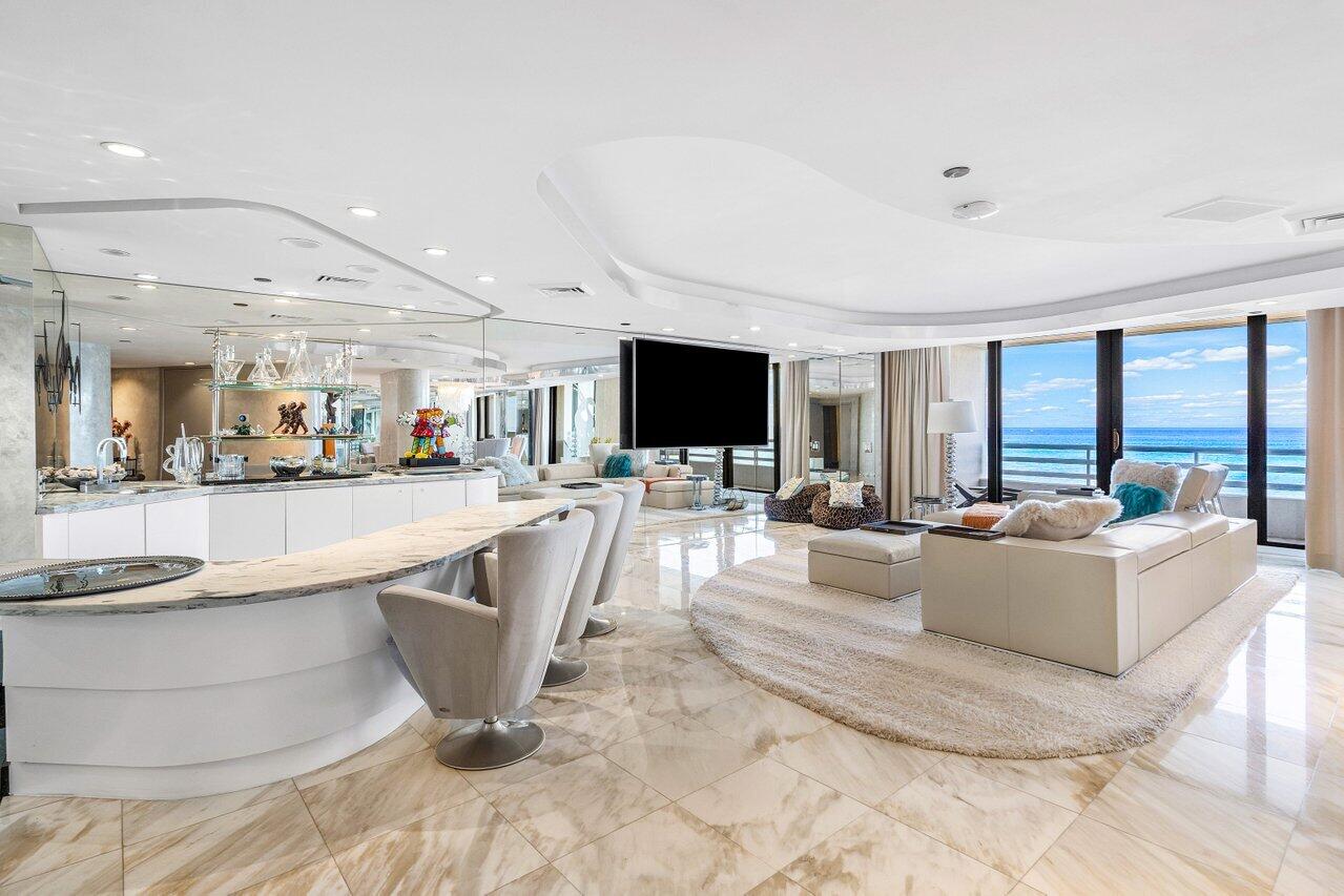 One-of-a-kind 4 BD (3 bed plus office) 4.5 BA in The Addison offers panoramic ocean views from nearly every room, framed by sliding glass doors that wrap the perimeter of the home. Built to be two separate units combined into one, the layout forms a striking circular design centered around a private elevator foyer, giving the entire home a rare and architecturally captivating flow. The interiors showcase iconic 80s-inspired design, from sculptural curves to LED ceiling lighting and creative glass paneling. It is an exceptional opportunity to modernize a truly distinctive space while preserving the architectural character that makes it so special. The kitchen features sleek, high-gloss cabinetry for a modern touch and overlooks the ocean so you can enjoy breathtaking water views while cooking or entertaining. A built-in bar just off the kitchen enhances the home's effortless entertaining potential. The primary suite is a true standout with sweeping ocean vistas, a private balcony, dual primary bathrooms, and three walk-in closets. On the opposite side of the residence, two additional ensuite bedrooms are connected by an expansive office or den; an incredibly versatile space ideal for working, hosting, or creating a separate lounge area. Endless views, endless light, and endless potential, this circular oceanfront residence is an unmatched opportunity to reimagine a home that already has extraordinary bones and incredible ocean views.   Positioned on the coveted shoreline of Boca Raton, The Addison On The Ocean offers an exceptionally private and refined beachfront lifestyle. With only 169 residences, this exclusive community is defined by expansive floor plans, breathtaking ocean views, and a level of service typically reserved for world-class resorts. Arrival is marked by an elegant covered entry, tranquil water features, manicured grounds, and full-service valet.  Inside, residents are welcomed by a sophisticated lobby that frames the Atlantic as a stunning natural backdrop. The building delivers a truly elevated living experience, featuring a newly redesigned on-site restaurant along with multiple outdoor dining options—whether poolside, under the gazebo, or directly along the oceanfront. A beautifully updated social space creates the perfect setting for entertaining, complemented by full-service dining that includes daily meals, takeout, and private catering.  Every detail is designed for comfort and convenience, with dedicated on-site management, 24-hour maintenance, and a professional concierge team available to coordinate services such as housekeeping, transportation, and vehicle care. Advanced security systems, continuous monitoring, and integrated resident communication platforms provide both peace of mind and seamless connectivity. Modern enhancements, including electric vehicle charging stations, further elevate the living experience.  Wellness and recreation are seamlessly woven into the lifestyle at The Addison, with multiple fitness centers, spa amenities, saunas, steam rooms, and massage services. Residents also enjoy a wide range of activities, from sports courts and water recreation to a dog park, game rooms, and a business center. Outdoors, the property features two newly renovated pools, expansive sun decks, an open-air lounge, fire features, and cascading waterfalls—creating a resort-like environment just steps from the sand.  Within this premier building, our listing at 1500 S Ocean Blvd, Unit 303/304 presents a rare opportunity to own a spacious, combined residence with exceptional layout potential and direct access to all of the community's luxury amenities—perfectly blending scale, location, and lifestyle in one of Boca Raton's most prestigious oceanfront addresses.