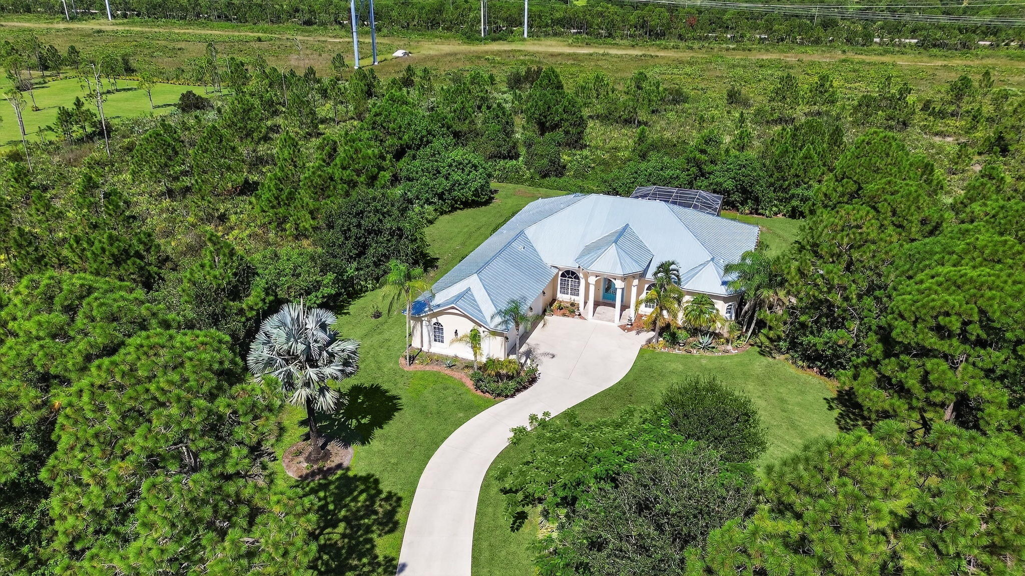 PGA Village estate home with plenty of room to build a guest house on over 4 acre homesite!!  Main house features 3871sqft,  4BR's, plus spacious office, 3BTH's, & oversized 3 Car Garage w/10ft ceilings. Enjoy a sparkling pool, expansive lanai, cabana bath, along with open & light-filled interiors. Oversized kitchen w/2023 appliances, centrally located featuring a butler's pantry perfect for entertaining! Owner's suite offers a sitting area, dual walk-in closets, his/her sinks, garden tub, & dual shower. Recent updates include 2025 Metal Roof, new lighting, fans, exterior paint 2023 & more. This private estate  in the Sabal Creek neighborhood of PGA Village is a rare find, take a private tour today! Explore the Prestigious PGA Village Championship Golf Course and Amenities!! Memberships are optional, golf, social and tennis! Community Pool, tennis, pickleball, playground, putting green, library, billiards and more! Manned gated entry! Close I-95, minutes to Tradition Square for ample shopping & dining, Saint Lucie West restaurants and Clover Park, home to the New York and St. Lucie Mets!