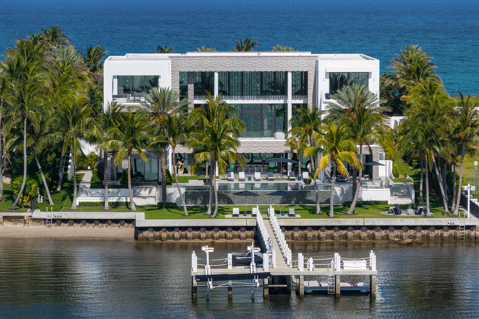 1940 South Ocean Blvd, Manalapan, FL 33462 - An Estate That Captures The Grandeur And Sophistication Of The World's Finest Luxury Hotel. Offered For The First Time, A Three Story 23K SqFt One-Of-A-Kind, Custom Built, Contemporary Seaside Masterpiece Stands Majestically Overlooking Nearly Two Acres Of The Florida Intracoastal Waterway And The Powdered Sand Shores Of Manalapan's Atlantic Ocean - Home To The Uber-Wealthy And Just South Of Americas Winter White House, ''Mar-A-Lago''. This Property Has Been Crafted From The Finest, Most Luxurious Resources, Fabrics, Stones And Natural Materials Available: Tunnel To Private Beachfront Cabana, Private Dock, Two Bowling Allies, Wellness Spa, Steam Room, Massage Room, Fitness Center, Movie Theater, Game Room, Craft Room, Elevator, Scullery Kitchen Personifying the spirit of relaxed elegance, this extraordinary gated, sun-drenched, three story, five bedroom, thirteen bath family home replete with underground tunnel to the 1,200 square foot beachside cabana (perhaps the largest in Manalapan) with accompanying oversized lawns and Oceanfront balcony stretches 150 feet across both the Ocean and Intracoastal Waterway, presenting nautical influences that suggest a breezy and serene palette - encompassing the essence of modern sophistication and coastal life. The underground tunnel offers a unique architectural feature, flawlessly connecting the main house to the lavishly appointed beachfront cabana. It ensures privacy and ease of access, making it convenient to enjoy the sun-drenched beach without stepping outside the boundaries of the estate. 

The Homeowners' natural flair for comfort was paramount when choosing each design element personally as the estates natural light and soothing aquatic tones of blues, grays, and sand invite a sense of peacefulness and balance, while blending the use of artisan hand-crafted tile work, marble, onyx, wood, metal, stone and glass along with the overhead glow from dramatic lighting fixtures in every room (each an individual work of art) add a heightened emotion of excitement. Each room boasts custom-built furniture that complements the architectural brilliance, creating a consistent yet vibrant visual narrative. The use of floor-to-ceiling windows throughout the home allows for an abundance of natural light to pour into every corner, creating a warm and inviting atmosphere. This thoughtful integration of natural light not only enhances the visible appeal but also contributes to the energy efficiency of the home. The interplay of light and shadow changes during the course of the day through custom fitted remote controlled black-out shades and sheer window treatments that follow the sun's path. The design elements of this home embrace a unique seaside escape, celebrating a way of life that treasures the beauty and tranquility of the coast - letting the soothing rhythms of the Ocean and the Intracoastal Waterway inspire you as you flawlessly and seamlessly move from room to capacious room without any interruption in style or mood.  

Upon entering this stately home through the grand oversized blue door, one floats like a dream past the open floor-plans formal dining room and luxuriously appointed living room and is immediately greeted by four 14-foot floor to ceiling limestone encased artistic wave design etched columns with accented lighting features there to remind you that the soothing Atlantic Oceans' surf is mere steps away. You can arrive in elegance to any of the homes three levels by either marble encased elevator boasting Intracoastal views through glass walls or a stylish cantilever wood staircase with marble and glass accents. To the south hall is a dramatic full-service backlit onyx bar flanked between twin rare and semi-precious lapis lazuli stone columns that create not only a striking focal point but also symbolizes a bridge between the earthly and the divine with elegance and artistry. A glass enclosed one thousand bottle temperature-controlled wine room and adjoining waterfront club room with its "11 Ravens" billiard table, bespoke design and meticulous craftsmanship makes this sophisticated space perfect for socializing and relaxation, inviting guests to unwind in elegant waters-view surroundings. Directly to the east one enters through glass encased sliding doors to the "Gentlemen's Office" displaying verdant views of the porte-cochere, front lawn and Ocean facing lounging area replete with glass fire-pit. Completing the middle / Ocean level, the gourmet kitchen with adjacent full service scullery kitchen equipped with state-of-the-art appliances and an abundance of custom commissioned sleek cabinetry seamlessly transition into multiple family and formal dining areas as well as the large west facing family room with outdoor covered loggia / grilling area using the Intracoastal Waterway as the  perfect scenic backdrop.

Spanning a sizable portion of the third floor, the oversized Homeowner's suite is a sanctuary of calmness, opulence and tranquility. This grand suite boasts breathtaking views of both the Atlantic Ocean and the Intracoastal Waterway. The suite features an expansive bedroom area adorned with luxurious custom furniture, including plush sofas, oversized chairs, cozy couches, marbled walls, wood floors and serving as the rooms' main focal point amidst all the lavish fabrics is a floor to ceiling custom crafted hide wall that carries onto the ceiling and down to a fireplace. The elegant design incorporates floor-to-ceiling windows that invite natural light to flood the space, creating a serene and inviting atmosphere. The individual his and her bathrooms within the suite are a masterpiece of design, exotic materials and comfort, equipped with a waterfront view freestanding sculpted soaking tub, multi-jetted showers, and expansive vanity areas adorned with jewel quality finishes. The use of high-end materials such as marble, onyx, and artisanal woodwork elevates the space, providing a moody spa-like experience. Adjacent to the bathrooms are three extremely generous sized, boutique-quality walk-in closets featuring custom-built cabinetry that provide ample space for a vast wardrobe. The suite also includes a private Oceanfront sitting room, perfect for relaxation. Flanking the east and west positions of the primary suite, sliding glass doors seamlessly flow onto the twin "Homeowners' Access Only" outdoor spaces where balconies, outdoor showers, and private hot tub await, perfect for enjoying picturesque Florida sunrises or sunsets. Continuing down the hall, the three additional guest bedrooms are adorned with en-suite bathrooms, plush bedding, custom-built furnishings, exotic stone counters, tiled or fabric walls, and expansive windows and balconies in each room that frame stunning views of either the Ocean or Intracoastal Waterway as well as the estate's lush surroundings. 

Upon entering the estate's entertainment and wellness lower level, immediately your senses are heightened by the unparalleled luxury, entertainment features and scenic Intracoastal views that surround you designed to elevate your living experience. The meticulously designed space boasts an array of amenities aimed at providing the utmost in relaxation and enjoyment. The lower level features a high-end Zen spa atmosphere complete with massage room, steam room, soothing multi-jetted showers with adjoining warm hued wood lockers providing a sanctuary for relaxation and rejuvenation; a state-of-the-art fitness center, equipped with the latest exercise machines promotes one's physical well-being, allowing you to maintain your physical health in style. A dedicated craft / hobby room (that can easily be converted into a sixth bedroom, if necessary, as it is fitted with its' own private en-suite bath). For those who appreciate indoor action-packed activities, the estate also offers a mind-blowing, one-of-a-kind two-lane bowling alley offering the most unique recreational experience; a movie