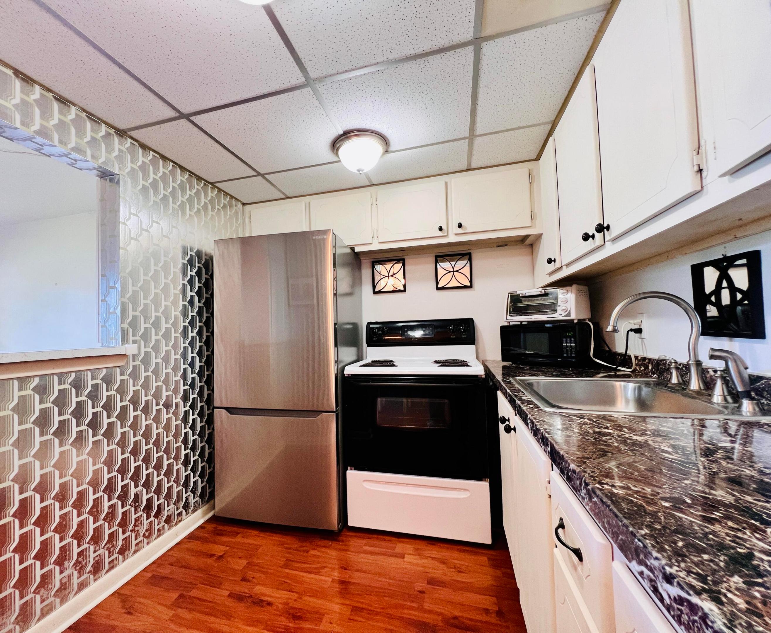 A DELIGHT WITH SPECIAL FEATURES IN 55+ CENTURY VILLAGE! Nicely Maintained FIRST FLOOR 1/1 With CENTRAL AC (Rare For a 1/1 Unit)! Pretty Kitchen With White Painted Cabinets and Granite Look Counters. Updated Full Bath Features A Step-in Shower. Upgraded Gleaming Wood Look Flooring Flows Throughout. Long Lanai Includes A Door For Easy Access to the Parking Area. Nicely Maintained Building With New Roof (2023), No Special Assessments, and Reserves! Fantastic Location Close to the Popular Kent Pool! Century Village is a Vibrant 55+ Resort Style Community Centrally Located In Desirable Palm Beach County, Florida! Century Village... is a 55+ Resort Style community with so much to offer - Much To Offer - shows, movies, clubs, pools, security, and transportation service. The Clubhouse features a theater, indoor pool, card room, community/party room, billiard room, shuffleboard, tennis, pickleball, bocce, and two outdoor pools, Numerous heated outdoor pools throughout the community. Separate fitness center with gym and outdoor heated pool & resistance pool. Two guarded gates and 24-hour roving security patrol.