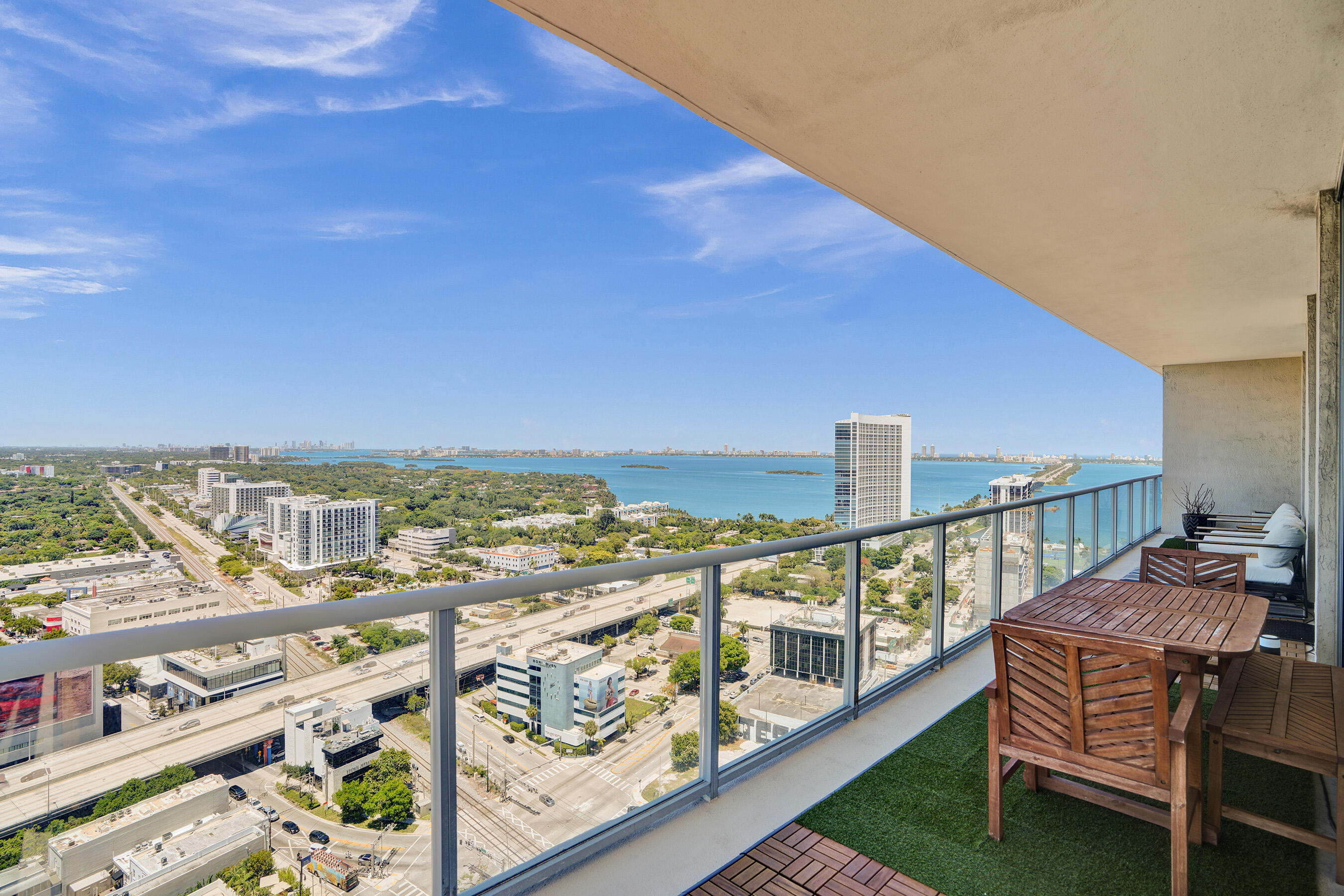 Luxuriously renovated high-floor corner residence at Two Midtown. This stunning 2BR+den, 2BA home boasts soaring 10-foot ceilings, floor-to-ceiling glass, and a massive 600 SF wraparound terrace delivering panoramic 270° bay and city views. The expanded layout features a seamless open-concept living area and a sleek, modern kitchen anchored by a custom functional island. The opened den offers total flexibility as an expansive lounge, home office, or easily enclosed 3rd space. Equipped with premium finishes and electric window treatments throughout. Enjoy resort-style amenities: heated pool, dipping pools, whirlpool, sauna, steam room, and a state-of-the-art fitness center. Includes 1 assigned parking space. Steps from the Design District, Wynwood, and Midtown's premier dining and shopping.