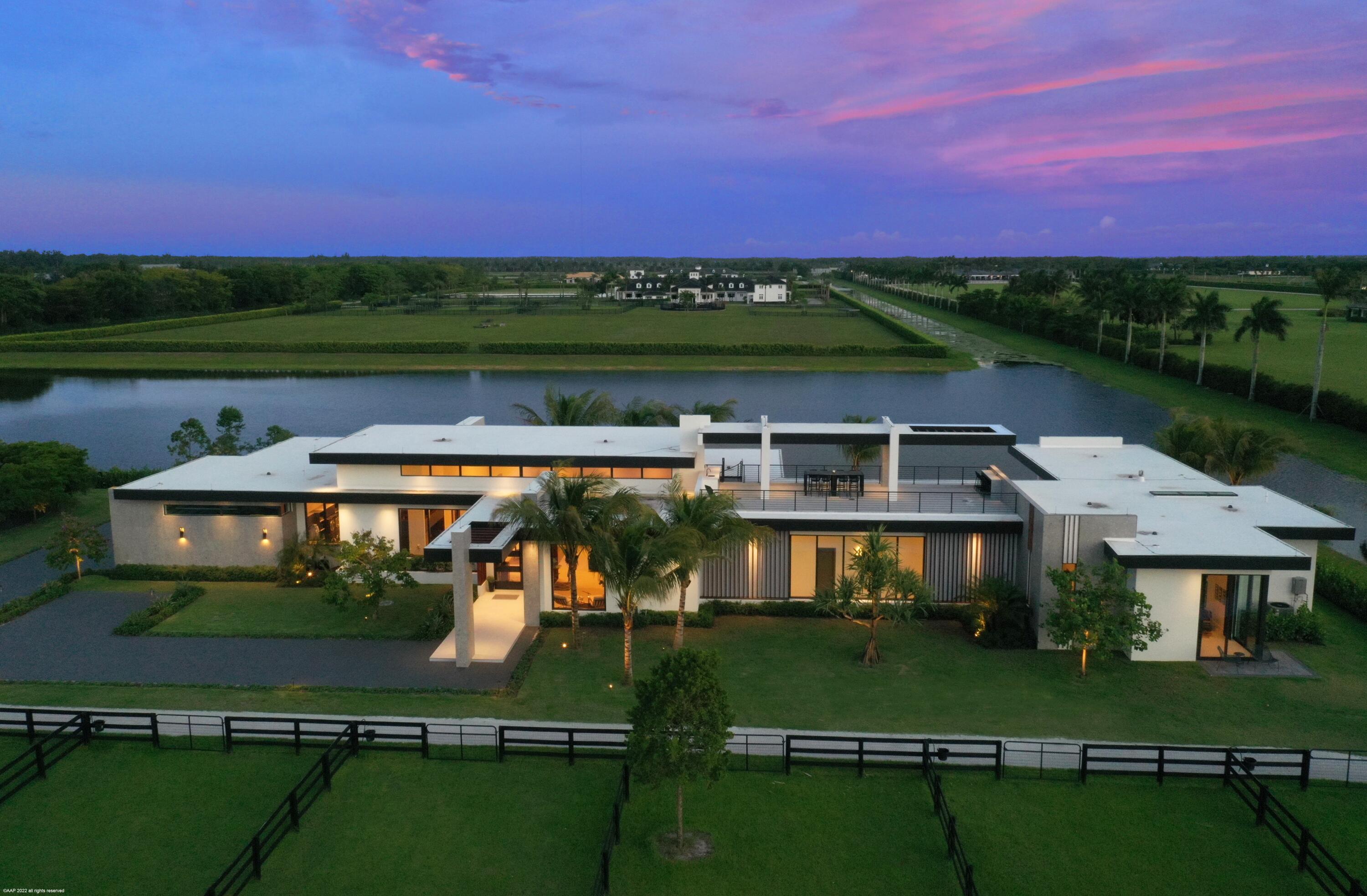 This awe-inspiring 5.24 Ac farm brings a breath of fresh air to equestrian architecture & design. Offered turnkey furnished, the home boasts open concept living w/ expansive walls of glass & views to outdoor spaces. The center-island kitchen offers Porcelanosa cabinets, quartz countertops, gas cooking, double ovens & large walk-in pantry w/ extra refrigeration. The master-suite showcases a luxurious dressing room & bath w/ a double-sided gas fire feature, digital shower & soaking tub. Entertain poolside at the summer kitchen or on the 2nd story sundeck bar watching sunsets over the polo fields. Riders will love the 8 stall courtyard stable w/ stunning tack room & viewing lounges, jumping arena, exercise track, hotwalker, treadmill & more. The Residence:

Kitchen Appliances:
Wolf double ovens & gas range
Plus speed oven
Liebherr refrigerators
Lepa wine cooler
Quartz counters
Extra refrigerator & freezer in walk-in pantry

Laundry Room:
Double machines
Krion counters
Sensor faucets

The Office/Den: 
Glass walls with views to the pool
Floating desks & bookcases.

24' Ceilings
12' Sliders
3 Zone AC (Living areas, 2 guest rooms, Master suite & 1 guest room).
48" x 48" Porcelain tile throughout

All bedrooms have in-suite bathrooms.
Bathrooms have custom cabinetry & Toto toilets.
Central breakfast bar area servicing all bedrooms.

Master bathroom shower has 3 body sprays, rain shower & handled with digital control.

Summer Kitchen & Patio:
House automated bug screens
Sink, BBQ with hood
Refrigerated drawers
Flat screen TV

The pool:
Infinity edge pool & hot tub
Automated pool & Jacuzzi with lighting & sound system throughout.
Gas heated with salt chlorination.

Rooftop Sundeck:
Tiled decking
Covered area
Sound system
Bar counter with refrigerator & sink.

Full house Generator (house only)
All hurricane windows and doors
4 Car garage: 10' x 22' doors with 12' ceiling. 
Finished floor.

Security:
9 Cameras (3 at house & 6 at the stable).
Gated driveway.
3-rail wood fencing with wire mesh.
 
The Stable:
8 Stall courtyard style
Custom tack room
The Barn has automated breathable hurricane screens on the aisleway with impact window shutters on each stall.
Owner's viewing lounge with full bath.
Phantom screens
rubber pavers 
2 Groom/Wash stalls inside.
Separate Vet/Farrier area.
3 wash racks outside with fans
Large staff break room with laundry & views to arena and paddocks.
Barn Powder room
Feed room
Storage room
Hotwalker
Treadmill
Jumping arena
8 Paddocks
Arena 126 X 245