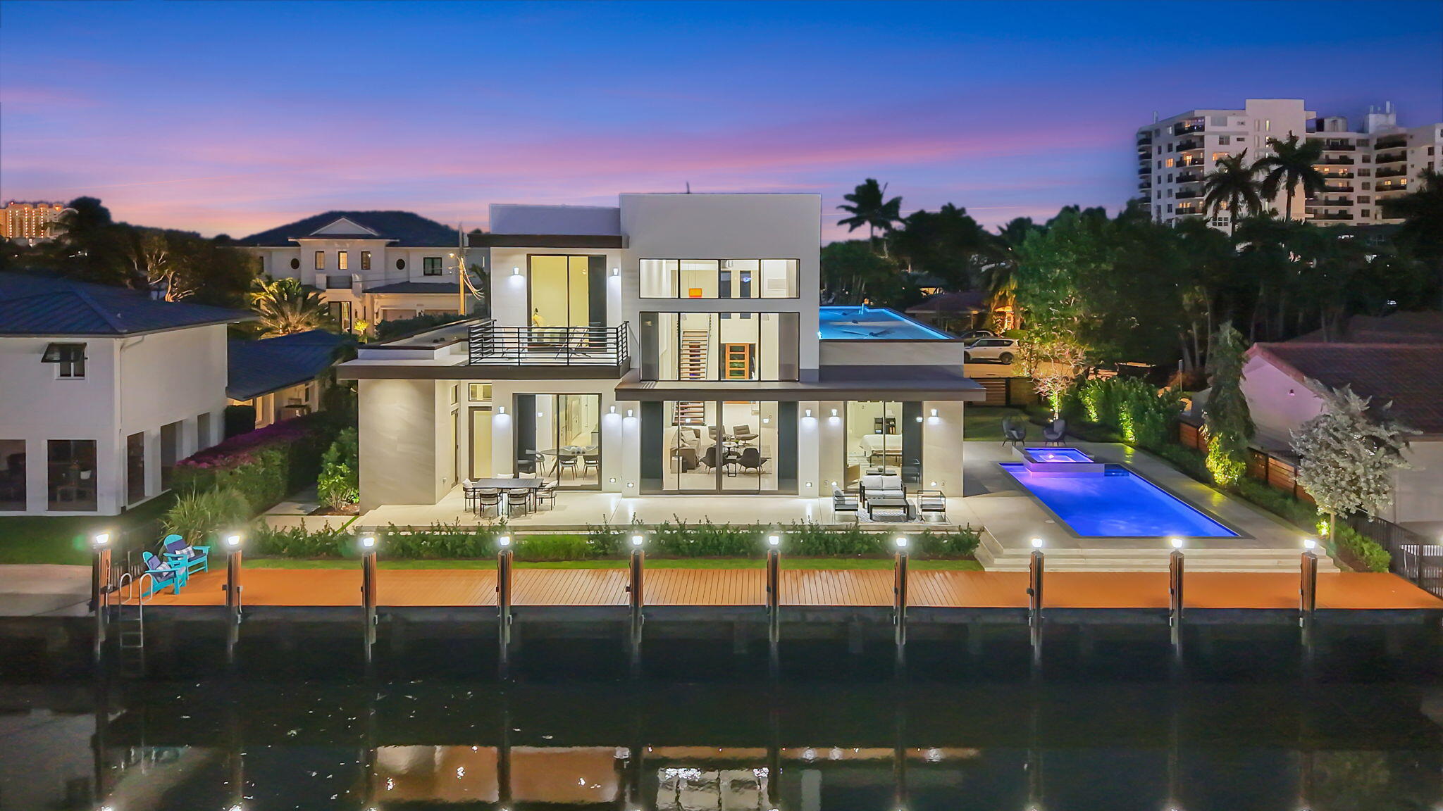 Introducing a stunning brand-new 2024 ground-up concrete waterfront estate, ideally situated just off the Intracoastal, featuring a 100-foot private dock with raised seawall and effortless ocean access. This modern-contemporary masterpiece exudes industrial sophistication, blending concrete, metal, and wood, with soaring ceilings, a striking staircase, and a split-bedroom layout. Expansive glass walls frame serene water views, while sleek, thoughtfully placed fireplaces add warmth and refined ambiance. Designed for entertaining, the open interior boasts gourmet appliances, integrated smart home systems, and a full-home generator. Outdoors, a private pool and spa complement the waterfront setting—a rare sanctuary for yacht enthusiasts and connoisseurs of elevated, sophisticated living.