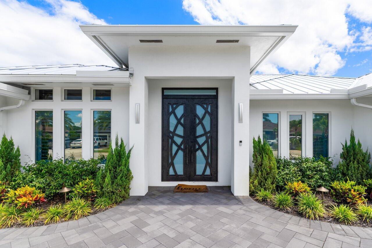 Everything you could want in a NEW HOME and MORE!   Welcome to your ultimate MOVE IN READY sanctuary with over 4,000 sq ft: Totally Renovated! The amazing lot offers total privacy with full lake and golf course views.... Nothing but Rolling Golf Course Fairways behind you!  Tall hedges on both property sides provide for total privacy for your Backyard Oasis:  Spa Pool, Oversized Hot Tub, Summer Kitchen and a full AC'd Cabana Bath!  Stone Deck with ample area for entertaining and lounging, pool with newly configured  Sun Shelf, All New Salt Pool Equipment w/full pool/spa heater (with Aqua-Link), and LED lights!  The property, front and back, has been landscaped to create a serene setting during the day with palms, flowering trees and bushes. At night, energy efficient decorative lighting makes this home sparkle!  Inside, a chef's kitchen with Thermador appliances & Taj Mahal quartzite countertops, Pantry, WINE room and wet bar, each area expertly designed with Custom Wood Cabinetry.   Soaring ceilings throughout the home add to the contemporary feeling and flow.  Beautiful office with 10' ceilings and custom built in wall of furniture with double sided desk.  Each bedroom is ensuite, plus 1/2 bath off kitchen.  The luxurious primary suite features a coffee bar, dual huge custom closets, and spa-inspired master bath with jetted tub and (2) water closets. Every energy efficient upgrade was incorporated including: new metal roof 2023, impact windows/doors throughout 2023, Custom 10' Front Door with matching custom office barn door, full-house generator and 500 Gal Tank 2023, new ACs/ducts and AC 2023, 3 tankless gas hot water heaters, and Icynene insulation. All lighting installed throughout this home is LED with many custom fixtures. This home has split garages with tiled floors, offering 2 - car spaces and 1 - golf cart garage on one side, AND A SEPARATE single car garage for your favorite toy on the other side. Garage doors are hurricane rated, insulated and have modern smoked glass windows adding to the overall modern look of this home. Boca Woods, a premier private mandatory membership country club, boasts 2 championship golf courses, tennis, pickleball, a newly renovated clubhouse with fine & casual dining, state of the art fitness center, spa & game room.   FEATURES:  Outdoor Paradise - resort-style backyard, perfectly designed for entertaining and relaxation. NEW 2023  Sparkling pool with sunshelf all-new equipment, gas heater, and Aqua-Link system Oversized spa  Covered seating areas with fans Custom summer kitchen with gas grill and Full 3 pc cabana bath (with A/C!) Professionally designed landscaping with lighting throughout Expansive paver circular driveway with parking for family and guests   Interior Highlights  Every detail of this ~4,100 sq. ft. residence has been thoughtfully crafted for style, comfort, and function.  Light-filled custom kitchen with Taj Mahal Quartzite countertops, large island, bar counter, pot filler, and Thermador appliances (including Gas Stove, & Column Refrigerator & Freezer) Custom pantry, family room, formal dining room, and LED-lit bar with wine room 3 spacious ensuite bedrooms plus 1 full and 1 half additional bathrooms Master retreat with coffee bar, dual custom walk-in closets, and spa-inspired bathroom with his & hers vanities, separate water closets, and luxurious finishes Custom office with double-seat desk and built-ins Solid 8' core doors, plantation shutters, and motorized zebra shades throughout  Smart & Strong Home Features  New metal roof  Full home Generac generator Impact windows & 8' sliders New insulated hurricane-rated garage doors (2-car, 1-car, and golf cart garage -all with level 5 commercial tile) Icynene spray foam insulation in attic 3 tankless gas hot water heaters All-new HVAC system & ducts LED lighting inside & out Ring doorbell with exterior cameras This home isn't just move-in ready it's better than new, with every luxury upgrade and energy-efficient feature already in place. Perfect for year-round living or as the ultimate entertaining retreat, this is a rare opportunity in one of the most sought-after communities.