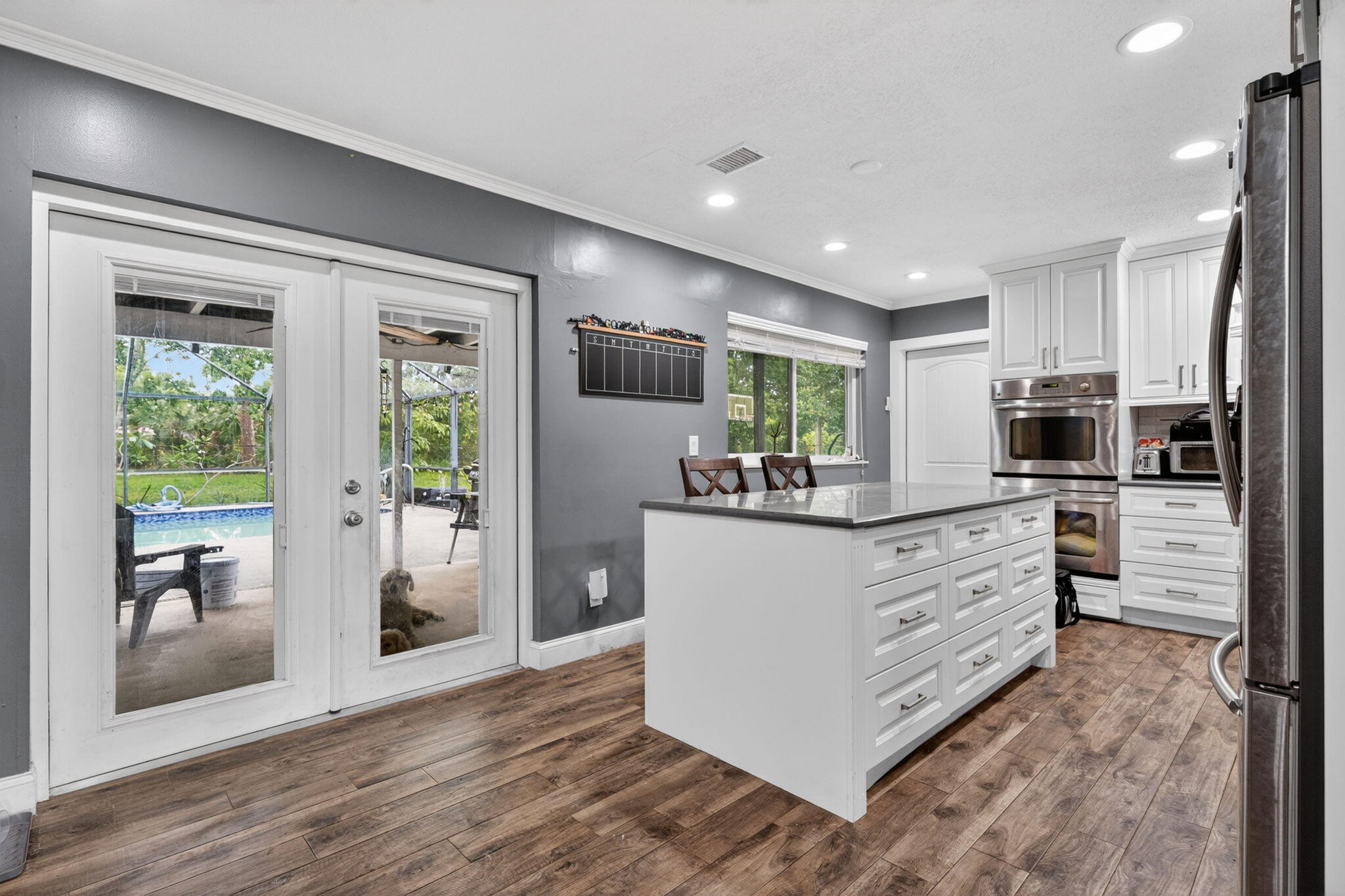 3-bedroom, 2-bath home w/ den & extra room, situated on a 1.12-acre lot in highly sought-after community w/ low HOA fee. Owner's survey reflects an approximately 200-foot-wide lot, measuring 279.20 feet on the left side and 195 feet on the right side. Updated island kitchen featuring double ovens & white cabinetry.  Main living areas showcase stylish wood-look tile flooring,  large windows fill interior w/ an abundance of natural light. Expansive living room creates a warm & inviting atmosphere, French doors from den & kitchen seamlessly connect indoor & outdoor living.  Enjoy the covered patio overlooking a screened-enclosed pool, all surrounded by a fully fenced yard w/ plenty of mature trees providing ultimate privacy & tranquility. Impact storm protection on all windows.