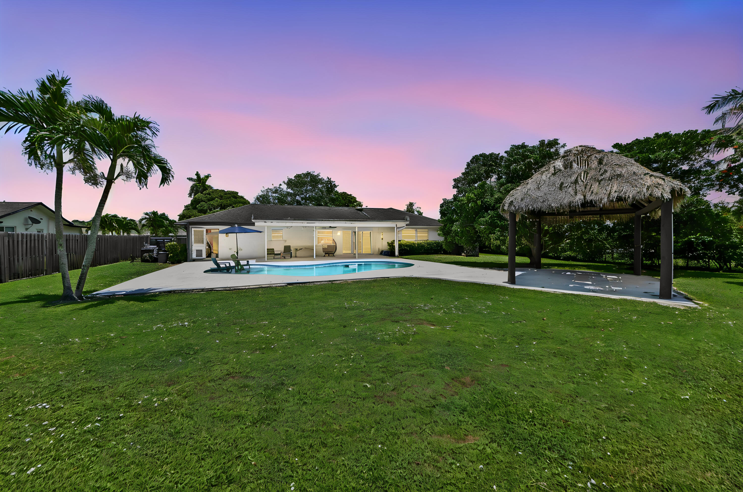 Welcome to 7635 Oakmont Drive in Lake Worth, a charming 3-bedroom, 2-bathroom single-story pool home located within the established Palm Beach National Golf and Country Club community. Offering 1,542 square feet of comfortable living space, this residence features a practical split-bedroom layout, a 2-car garage, and full impact windows and doors for added security, efficiency, and peace of mind. The home's single-level design makes everyday living simple and convenient, while the inviting interior provides a comfortable setting for relaxing, entertaining, or making the space your own. The backyard is where this property truly shines. With views of the canal and offers a private outdoor retreat complete with a sparkling pool, upgraded marble pool decking, and plenty of space to enjoy South Florida living. A large tiki hut creates the perfect shaded gathering area for weekend barbecues, poolside lounging, or outdoor dining with peaceful water views in the background. The generous lot size adds to the sense of privacy and openness, giving the property a relaxed tropical feel.  Located in a well-established Lake Worth neighborhood, this home blends practical everyday features . Whether you are looking for a move-in-ready primary residence, a seasonal getaway, or a home with standout entertaining space, 7635 Oakmont Drive offers a wonderful combination of comfort, convenience, and Florida lifestyle appeal this property is a standout opportunity.
