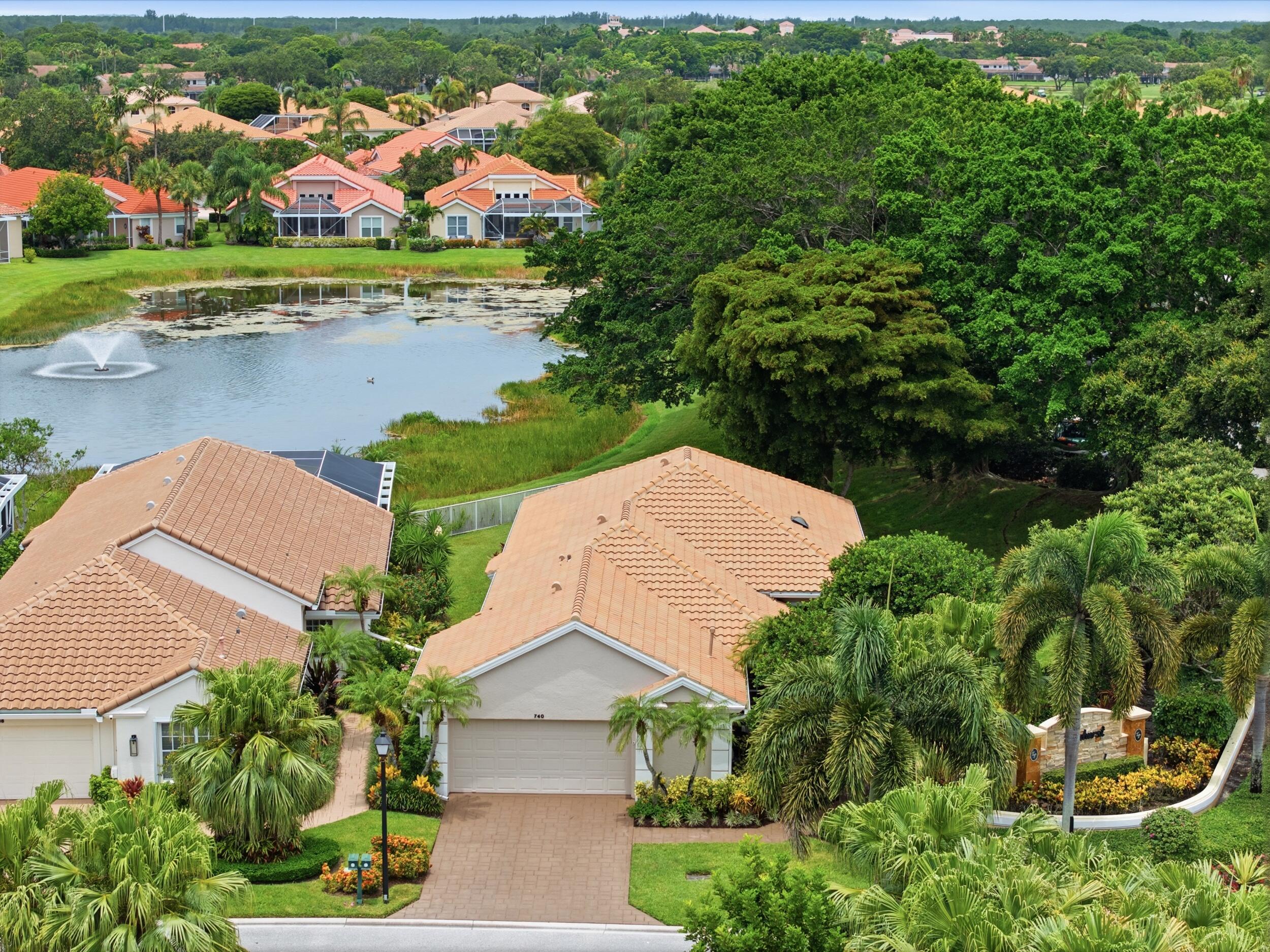 Framed by majestic banyan trees and overlooking a tranquil lake, this 3-bedroom, 3-bathroom residence offers a serene setting within PGA National. The impact glass-enclosed sitting room seamlessly extends the living space, bringing the beauty of the outdoors inside. The eat-in kitchen is filled with natural light from a charming bay window and breakfast nook and features white cabinetry with glass display uppers, granite countertops, a glass subway tile backsplash, white appliances, and a gas range. Architectural archways add character throughout the home, while white tile flooring flows through the main living areas. The spacious primary suite enjoys peaceful views of the backyard and lake through a large picture window, and there are two custom built-in closets. The primary bath is appointed with a soaking tub, walk-in shower, double granite vanities, stone walls, and a Woodbridge smart toilet. Two additional bedrooms and full bathrooms provide comfortable accommodations, including a renovated guest bath with coastal-inspired stone flooring and a convenient cabana bath. One bedroom is being used as a den. Outdoor living is equally inviting with an extended tiled patio, an automatic retractable awning with integrated lighting, and a spacious backyard offering ample room for a future pool. Mature banyan trees provide shade and character, while the landscaped yard and double picket fence create an inviting setting to relax or entertain. Additional highlights include impact glass, accordion shutters, automatic zebra shades, laundry room with sink and cabinetry, built-in garage storage, roof replaced in 2016, and a 2025 water heater. Located just steps from the community pool, this home is nestled within Eagleton, one of PGA National's most sought-after communities. Residents enjoy the security of a gated neighborhood and the opportunity to experience the renowned PGA National lifestyle, with optional memberships offering access to six championship golf courses, racquet sports, and seven restaurants.