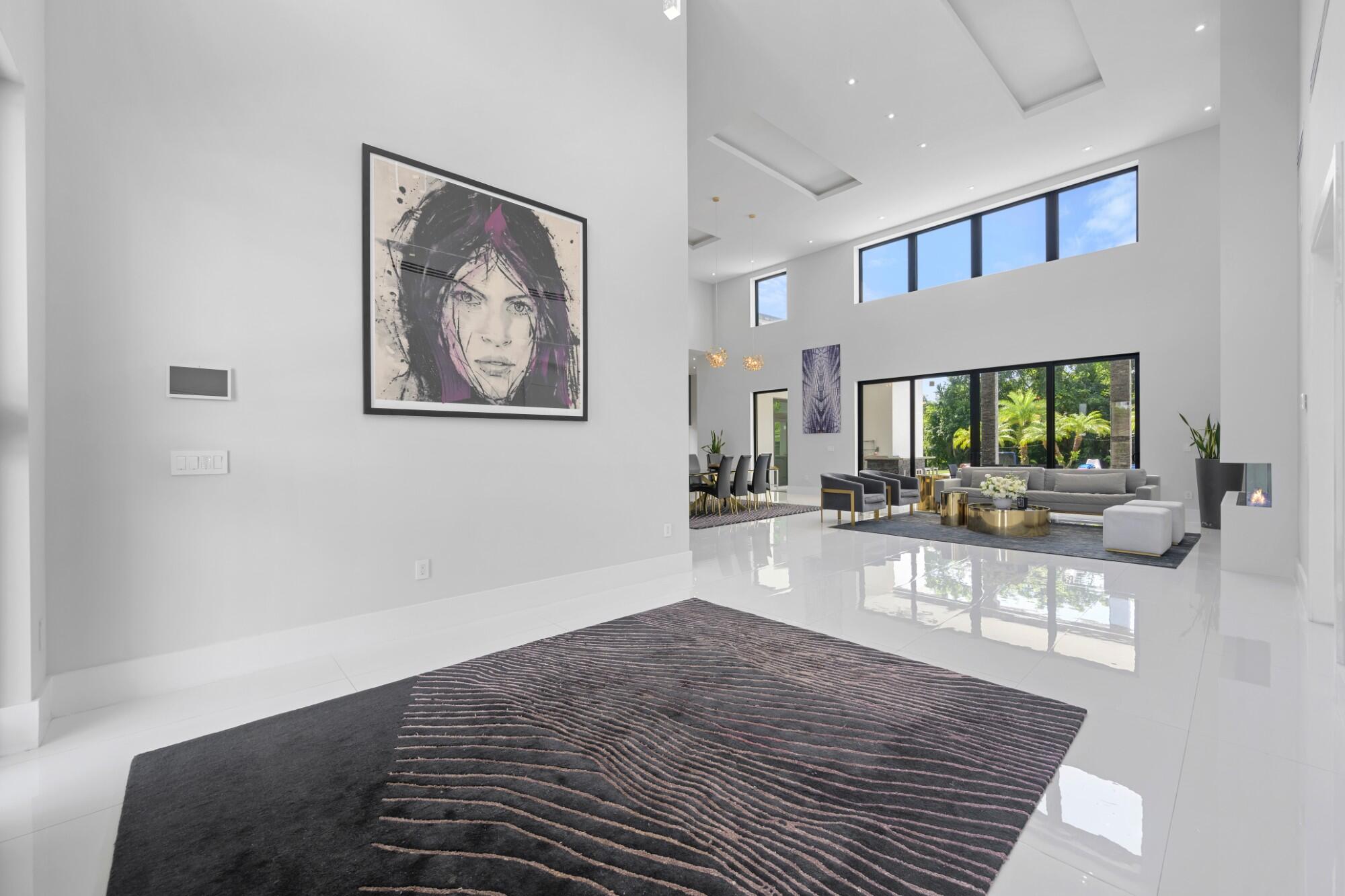 Modern masterpiece on expansive grounds, boasting soaring 20-ft ceilings, sleek porcelain floors, and a chef's kitchen with custom cabinetry and quartz counters. Six spacious bedrooms each offer private ensuite baths and custom walk-in closets. The lavish primary suite features a serene sitting area, dual walk-in closets (his and hers), and a luxe glam room with built-ins for shoes, handbags, and makeup. A private elevator provides access to the second level, where you'll find a stunning home theater, bar, and kitchen. Outdoors, indulge in resort-style living with a saltwater pool, spa, summer kitchen, covered terrace, and an impressive driveway with a 3-car garage. Smart, energy-efficient, and built for ultimate contemporary living.