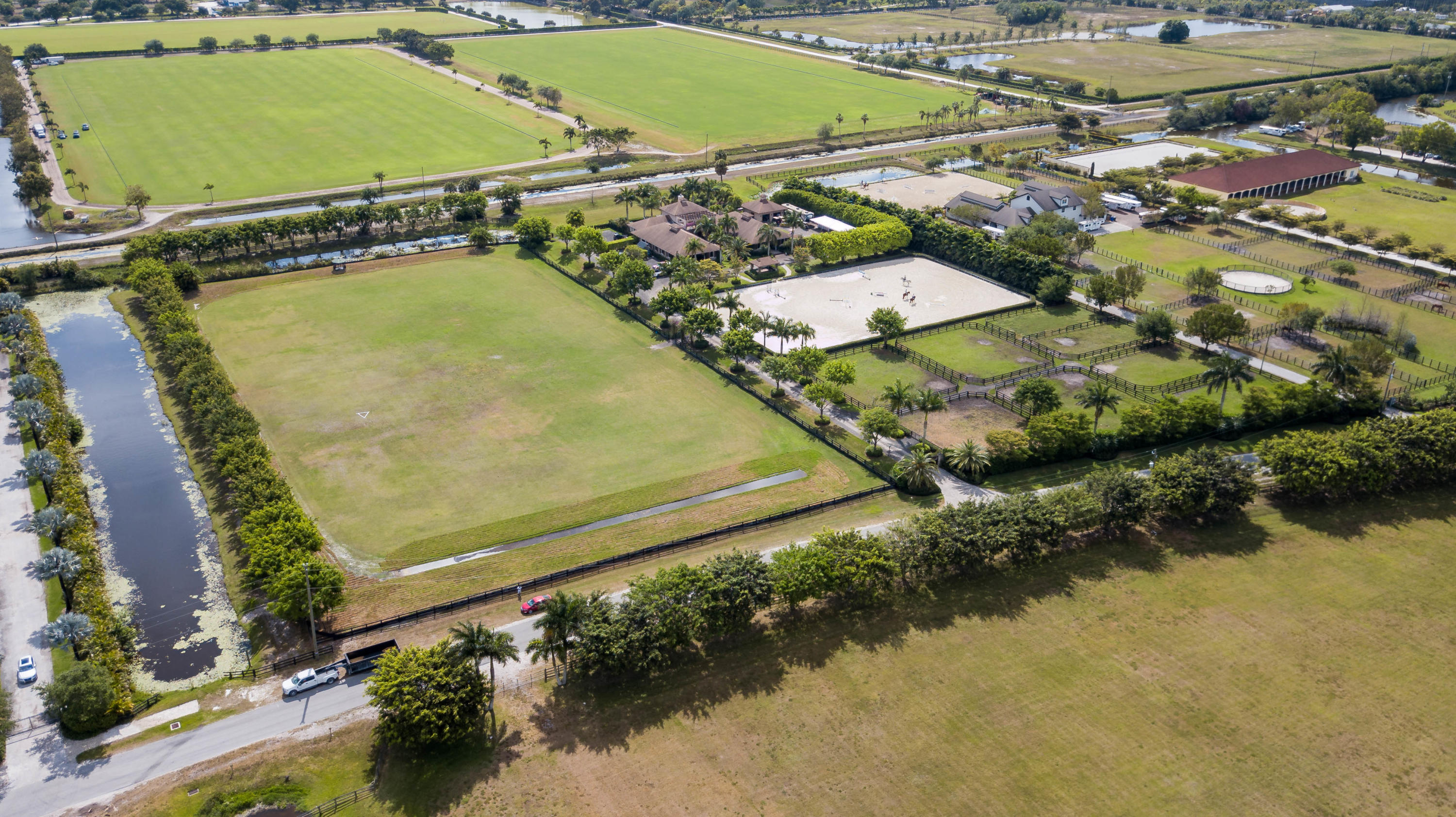 This upgraded professional equestrian facility is located in Palm Beach Point East and is hacking distance to the show via bridle paths. The magnificent, gated property is situated on two parcels totaling 10 acres and boasts a regal, 20-stall barn and residence, new riding arena, 7 paddocks, and a 5-acre derby field. The barn's U-shape design features wide cobblestone aisleways, vaulted wood paneled ceilings with recessed lighting, 20 well-ventilated stalls, 4 hot & cold wash stalls, a large tack room, and a serene, garden courtyard. The expansive 150' by 250' riding arena features new, all-weather footing and is accompanied by a new covered and elevated viewing deck. The recently renovated, main-floor owner's quarters features a living area, dining room, fireplace, screened and covered lanai, and a gorgeous, newly redone pool area with a spacious Travertine tile deck and tropical landscaping. An elegant center staircase in the courtyard leads up to the second level manager's quarters, which offers a spacious deck with a pergola and a bird's eye view of the grounds. Other prominent features include a detached garage with an exterior RV-Hook up, an abundance of parking space, and a stately pavered driveway entrance with automatic gates and designer landscaping.