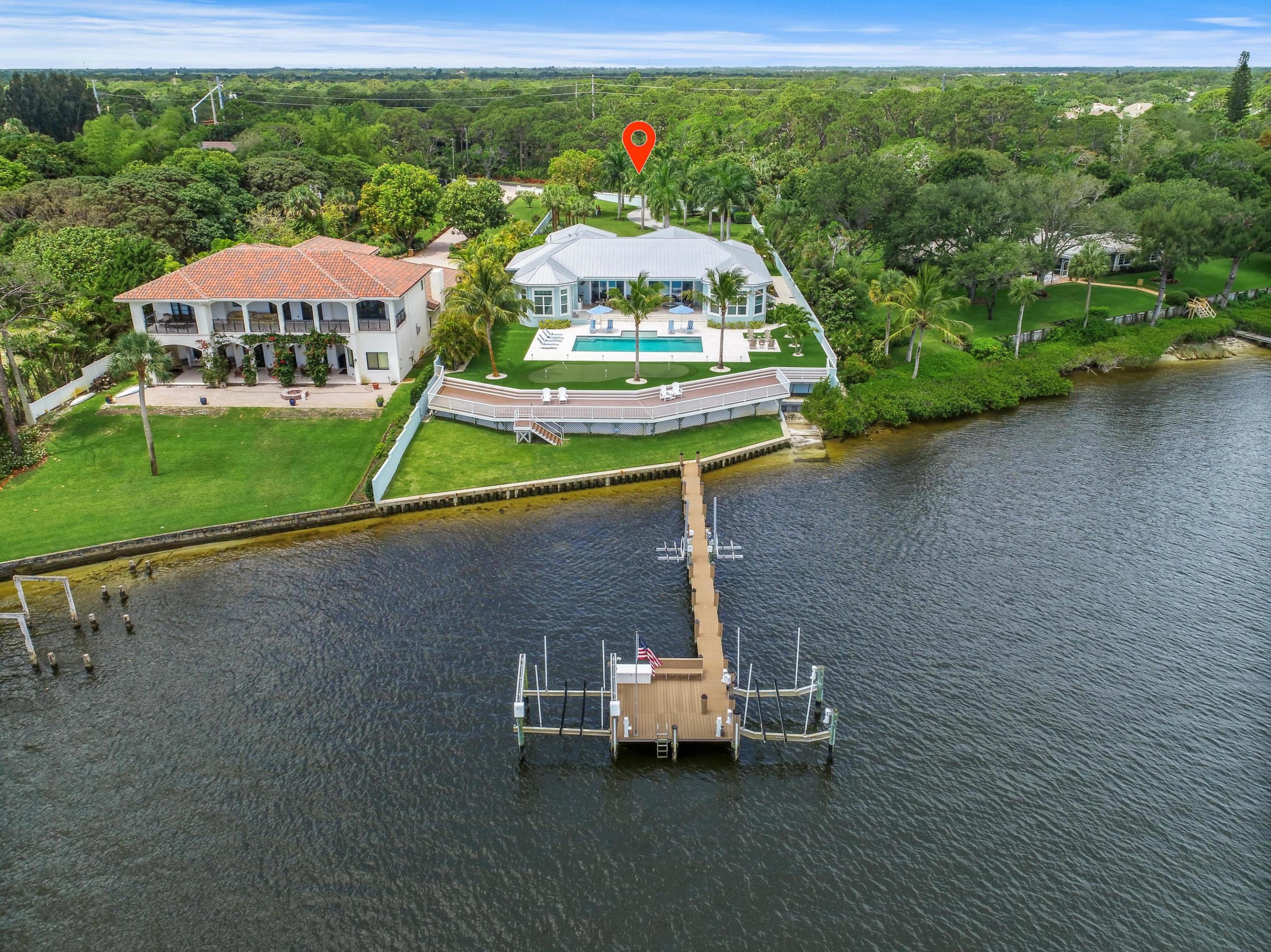 Nestled along the serene waters of the Loxahatchee River lies this beautifully crafted custom home built in 2015 by The Elite Companies on 1.25 acres. This oversized home-site features panoramic views of the Loxahatchee River and is just 5 minutes to Jupiter's waterfront restaurants and the blue waters of the Jupiter Inlet.  Attention to detail was paramount in constructing this concrete block home with hurricane rated impact windows and doors. The architecture is British West Indies with a standing seam metal roof and metal clad and glass hurricane entry doors. Inside you will find fine crafted walnut hardwood floors in the main living areas, custom wood shaker style maple cabinets in the open kitchen, granite countertops with a beveled edge and professional series Thermador... stainless steel appliances. The trim package is better than most homes twice this price point with custom built-ins in the great room, study, club room and custom millwork in the master and guest bedrooms. The 1st floor master suite features... 
outstanding interior design details that will not disappoint anyone in this price range. In the master bathroom, you'll find a luxurious spa-inspired design with an oversized frameless glass shower, contemporary free standing tub, double vanities, custom wood cabinetry and granite vanity tops. The porcelain tile walls have been book matched throughout with light fixtures that will excite even the most discerning of tastes. All closets come with wonderfully designed hand crafted built-ins for clothing, accessories and shoes. The guest suites are ample, cozy and warm, all with walk-in closets and en-suite baths. Outside enjoy grilling steaks in the summer kitchen all while lounging around the grand covered patio with motorized phantom screens. After a long day on the boat, relax in the low maintenance synthetic turf back yard or swim in your professionally designed heated pool and spa with fiber optic lighting. Hone your putting skills on the professionally installed putting green.  For the boating and fishing enthusiast, the Trex dock features two jet ski lifts, a boat lift, snook light and fresh water and electric at the dock. This is Jupiter waterfront living... Perfected.