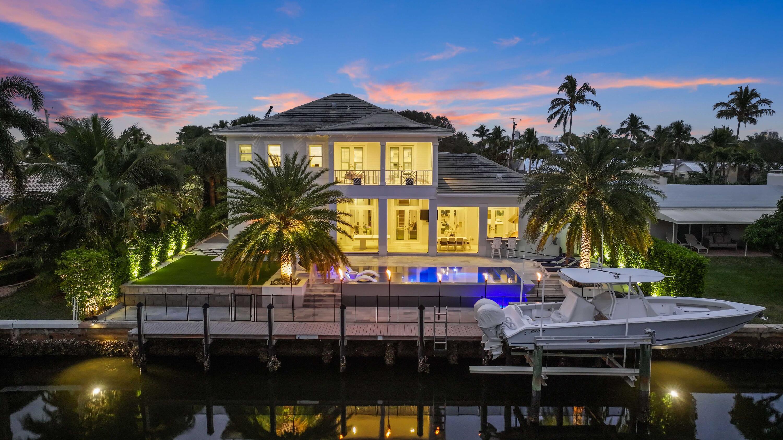 STUNNING 4 BR/ 6.1 BA FURNISHED DIRECT WATERFRONT HOME with DOCK & DIRECT OCEAN ACCESS. Professionally designed & decorated. This British West Indies-style home is an absolute masterpiece. The open-concept main living area features beautifully coffered 12-FT ceilings, hardwood floors throughout, impact windows/doors, electric shades in the living room and master bedroom. The chef's kitchen features JennAir stainless steel appliances, a gas range, double ovens, a farmhouse sink, an oversized island, 2 wine refrigerators, and a massive pantry. Both upstairs and downstairs laundry rooms and master suite is on the main floor. Step outside to your private paradise. The resort-style infinity pool and spa with a vanishing edge and sun shelf are surrounded by elegant marble decking... ...The pool features a glass bead finish, a saltwater system, and is complemented by a cabana bath and outdoor shower. Entertain effortlessly with a summer kitchen, fire feature, gas tiki torches, and lush tropical landscaping combining natural grass and turf. Enjoy 90 feet of waterfront with a 16,000-pound boat lift, dock lighting, and ramps for easy boat access. With no fixed bridges and space for up to a 65' boat, this property is a boater's dream. Additional features include: Sophisticated security system, upgraded driveway pavers, and exterior lighting package. Prime Location - Just steps away from the North Palm Beach Country Club.