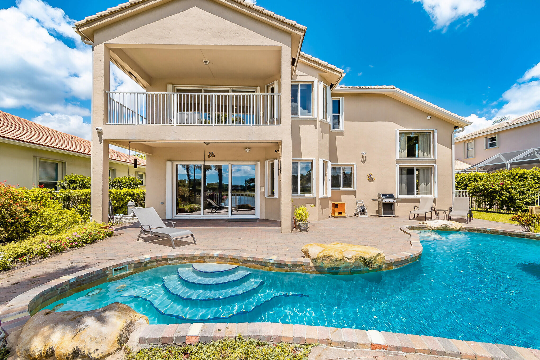 Discover refined luxury in this newly updated 5-bedroom, 3-bathroom lakefront estate in the prestigious Isles at Wellington. The spacious interior features soaring vaulted ceilings, an open chef's kitchen with a large island, and a primary suite with a private balcony overlooking serene water views. Step outside to a fenced backyard oasis with a tropical saltwater pool. Perfectly positioned for the active lifestyle, this home is just a golf cart drive from Wycliffe Country Club, moments from the Wellington Sports Academy, and near the Wellington International Equestrian Center. Enjoy resort-style amenities and access to top-rated schools like Panther Run Elementary. Turnkey and ready for you!