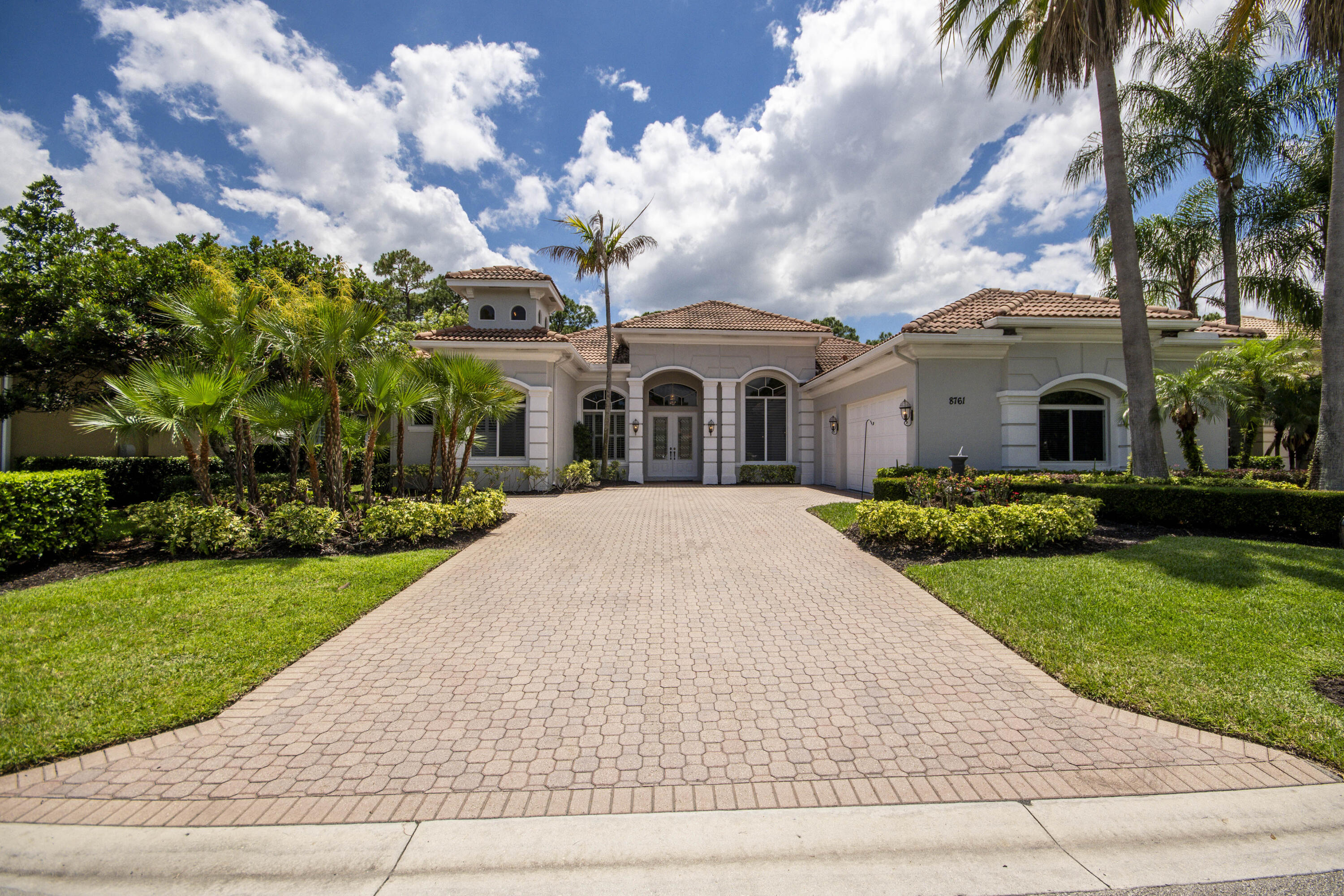 A private backyard oasis with a screened pool, outdoor kitchen, and peaceful golf course views creates the perfect retreat in this spacious high-end home located on the 7th fairway of the Wanamaker Course in PGA Village. Tucked within the desirable Spyglass community, this beautiful home offers 4 bedrooms, 4 full baths, 1 half bath, a dedicated office/den, and a 3-car garage across more than 3,200 square feet of living space. As you enter, you'll enjoy soaring tray ceilings and expansive views of the screened lanai and pool area. Tile flooring flows throughout the main living areas, while large windows and sliding glass doors fill the home with natural light and highlight the lush outdoor setting. The spacious kitchen features light wood cabinetry, granite countertops, stainless steel  appliances, a Bosch dishwasher, wine fridge, center island, and views of both the family room and pool area—perfect for entertaining. The family room offers additional dining space and direct views of the backyard paradise. The primary suite is a peaceful retreat with private access to the pool area, multiple windows overlooking the backyard, and a spacious en-suite bath featuring dual vanities, a frameless shower, soaking tub, and abundant storage. Additional bedrooms provide comfort and flexibility for guests or family. Step outside to enjoy the fully screened lanai complete with an outdoor kitchen, BBQ, refrigerator, tropical landscaping, and tranquil golf course views peeking through the trees. Additional highlights include a new A/C, new water heater, and an assumable VA loan at 3.25% for qualified buyers. Residents of PGA Village enjoy resort-style amenities including championship golf courses, tennis, pickleball, fitness center, clubhouse, pool, sauna, playgrounds, and more, all without mandatory golf membership requirements.