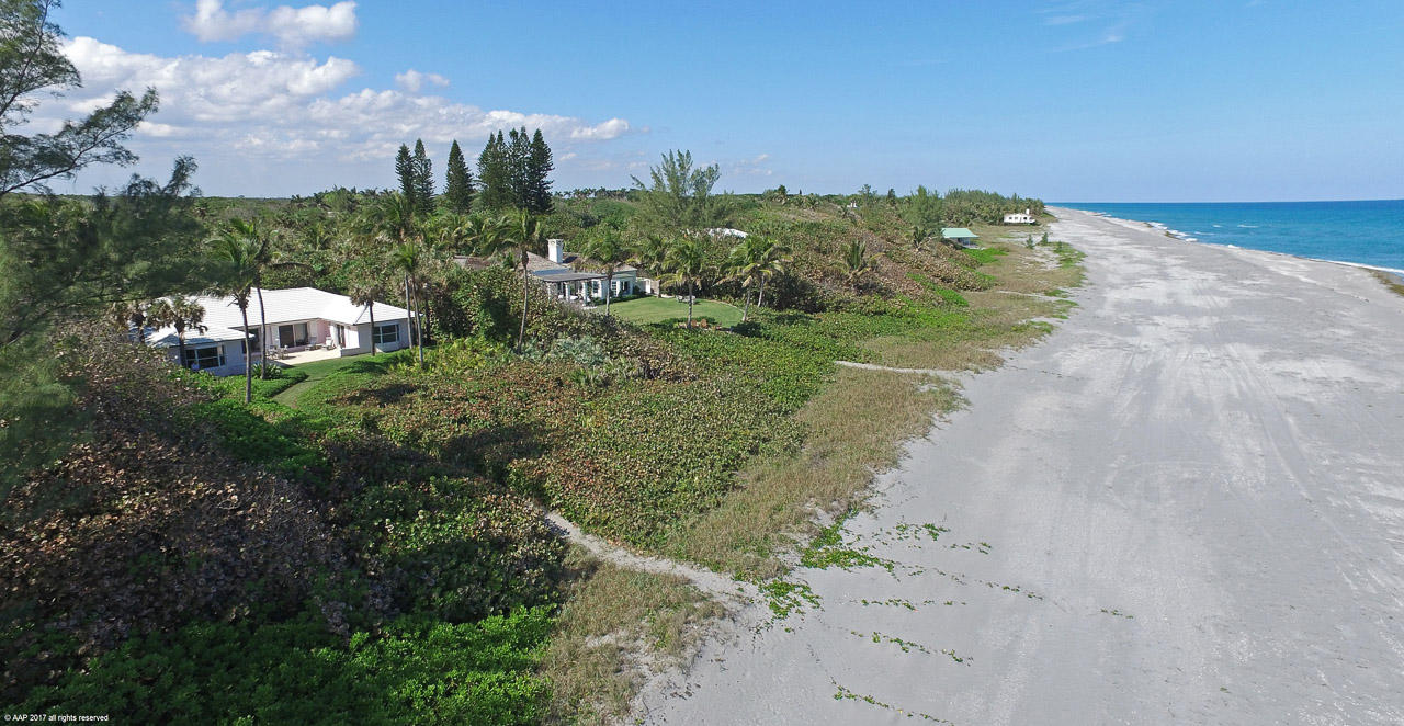 A long private drive surrounded by lush landscaping and tropical gardens opens onto this wonderful direct beach front property on the south end of Jupiter Island.  The beautifully decorated main house includes three bedrooms and features glorious ocean views from the major rooms. A separate two bedroom two bath guest house sits across the inviting and expansive pool area.