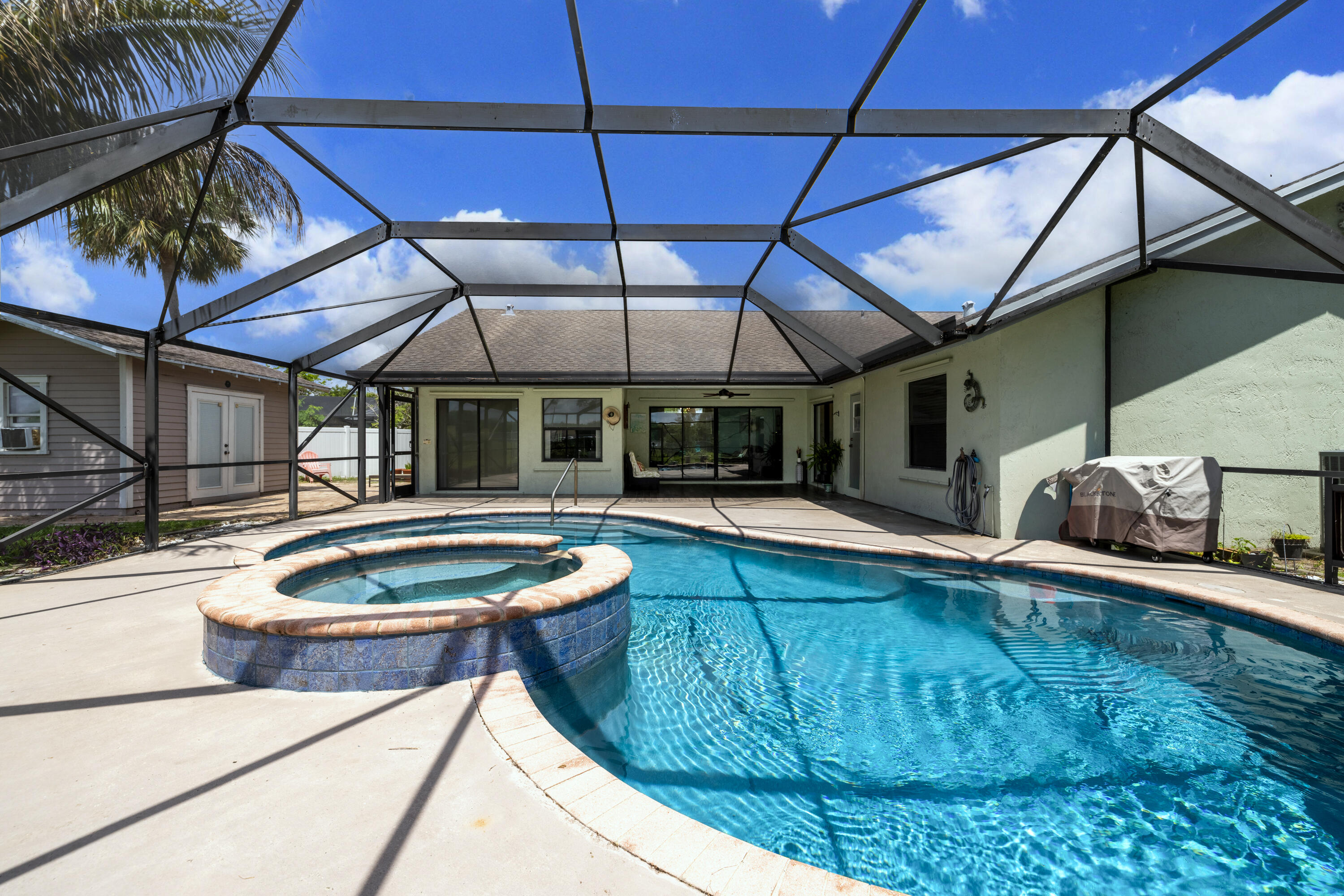 Discover the perfect blend of indoor and outdoor living in this 4 bedroom, 2.5 bathroom pool home on a 0.37 acre CUL-DE-SAC lot in a LOW HOA community. NEW ROOF being installed in June 2026. Tile plank flooring runs throughout the home. The kitchen features butcher block and marble tile countertops, stainless steel appliances, a gas stove with a vent, ample cabinetry, and a pantry. The bright, spacious primary suite includes a walk in closet, an en suite bathroom, and direct access to the pool. The laundry room offers a full size washer and dryer. A standout feature is the detached shed, which includes a Murphy bed, electricity, and Ethernet, plus an outdoor shower - ideal for guests, hobbies, or a quiet workspace. Enjoy the saltwater, screened in pool and the privacy of a fully fenced  yard. The 2 car garage and expansive driveway can accommodate up to eight cars. Additional features include a 2023 water heater, generator hook up, and the pool was refinished in 2022. Located in Lexington Estates, this area has A-rated elementary and middle schools and a B-rated high school. Minutes from shopping, dining, the Turnpike, and I 95. The beach is 8 miles away and PBI Airport is 14 miles away. All measurements are approximate. Be sure to view the 3D virtual walkthrough.