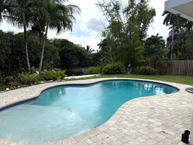 Sought after Lloyd Estates pool & waterfront home across from park-like setting. (no homes) Over 1600 sq. ft of Spacious open living areas. Open kitchen, dining, and living room overlook the pool & water. Triple split bedroom floor plan with updated primary bathroom. Separate laundry room with full size washer and dryer. Roof is 6 years old, tile floors throughout, lot almost 1/4 acre with private fenced in yard with open patio off main living area perfect for relaxing, entertaining & BBQ's. Home is set off beautifully tree lined street. Lloyd Estates park is 2 blocks away, walk to dog park, Easterline Park, Publix, & Crunch Gym. Minutes to Wilton Drive, the beaches, I-95 & Turnpike. Don't miss this opportunity to enjoy the true South Florida living!
