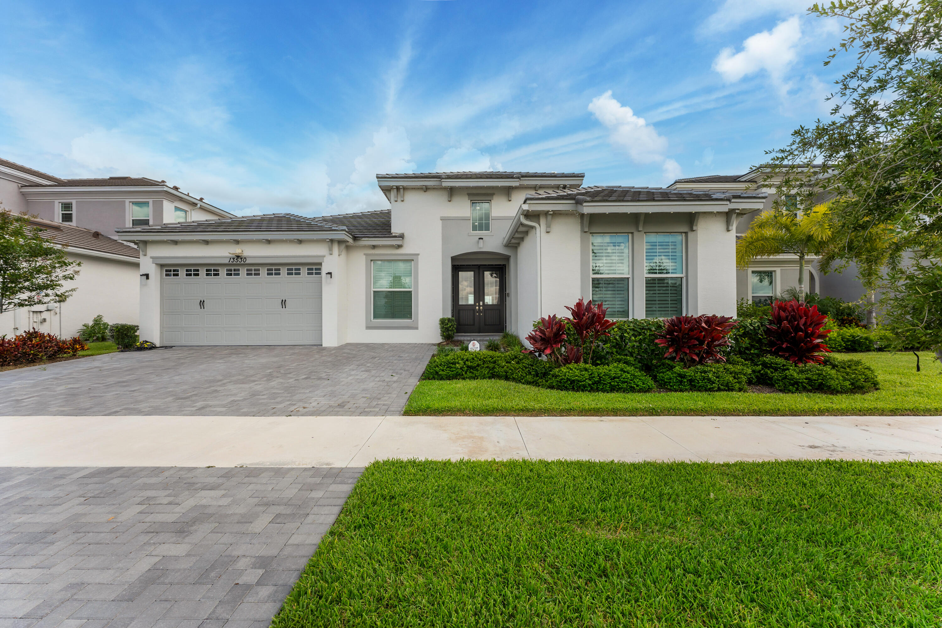 RARE DOUBLE WATERFRONT LOT! One of only a select few homes in all of Westlake offering stunning water views from both the front and rear of the property. Located in The Pines, one of the most sought-after neighborhoods within Palm Beach County's newest city, Westlake, this exceptional single-story residence combines luxury, flexibility, and an unparalleled setting.  Featuring over 3,100 square feet of thoughtfully designed living space, this open-concept floor plan is filled with abundant natural light and offers a highly functional layout. The home includes 5 bedrooms and 4 full bathrooms, along with multiple den/flex spaces and a separate hobby/media/theater room, providing endless possibilities for remote work, recreation, fitness, or multi-generational living. The upgraded interior showcases premium finishes throughout, including impact glass windows and doors, elegant 6" plank tile flooring, upgraded cabinetry, custom 9-foot barn doors, and upgraded vanities in every bathroom. The gourmet kitchen is highlighted by a farmhouse sink and faucet, impressive 3" mitered-edge quartz countertops, and an oversized extended island that serves as the centerpiece for entertaining and everyday living.  The luxurious bathrooms feature two large frameless glass showers, creating a spa-like atmosphere. The home is also pre-wired with high-speed network cabling, delivering enhanced connectivity for modern living.  Combining spacious single-level living, extensive upgrades, versatile living areas, and one of Westlake's most desirable double-waterfront homesites, this property represents a rare opportunity to own a truly exceptional home in one of Palm Beach County's fastest-growing communities. Westlake Adventure Park amenities include a lagoon pool with a 3-story slide, a splash pad, cabanas, lawn space for parties, an outdoor concert pavilion, basketball courts, an adult pool clubhouse (lodge), a playground, a dog park. As an owner, you also have access to Westlake's Adventure Park.