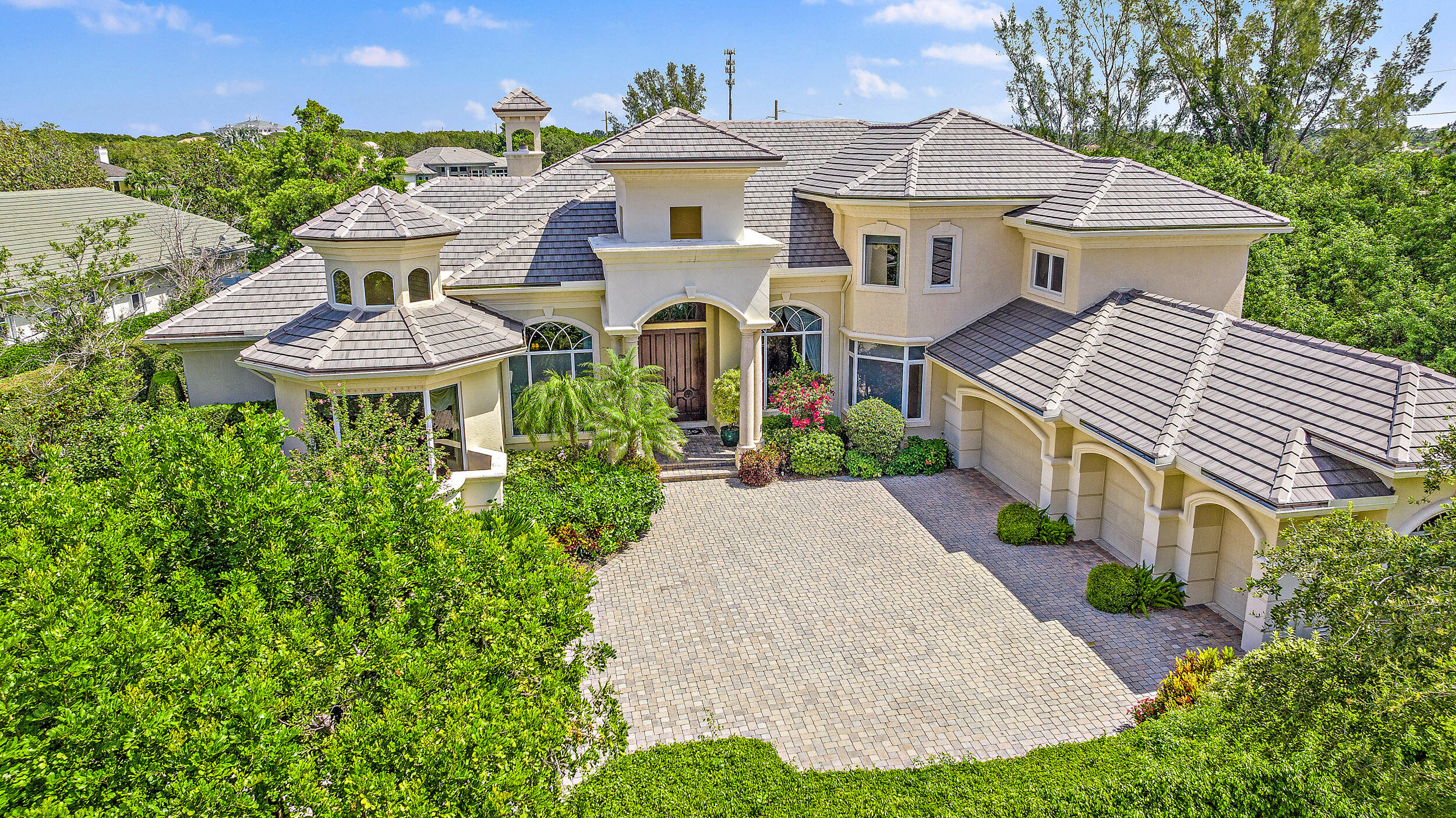Situated on Intracoastal Terrace in a unique private setting, this home offers a new family endless opportunity. Every option for entertaining family and friends can be accommodated in this fabulous enclave. With more than 7,700 sq. ft. under air there is space for the largest of family gatherings and reunions. The ground level offers three ensuite bedrooms. The primary suite is an oasis of tranquility, tucked away in its own wing. Presenting a lovely sitting room, his and her baths and enchanting views of the gardens and pool. Two very large walk-in closets complete the suite. The common space, formal living room, family room and dining room boast light-filled rooms and sparkling views. A large richly paneled library is perfect for reading a book, paying the bills or watching golf. Two additional ensuite bedrooms are located on the second level for a total of five ensuite bedrooms. A large three car garage and expansive storage make this home complete. All this just a short golf cart ride to the first tee, fitness center and practice tee. Come home to the Jupiter Hills lifestyle! Please note this home has impact windows and six windows have shutters.