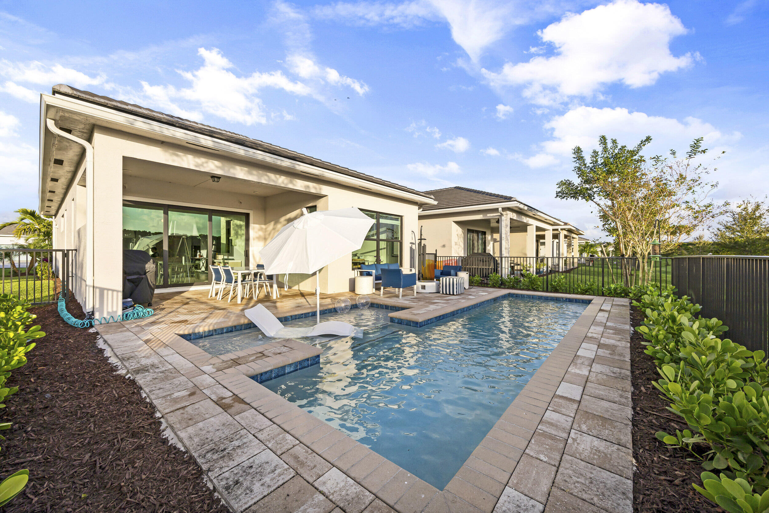 This contemporary retreat-style home offers 3 bedrooms, a versatile den, and 2 baths. The home welcomes you with upgraded flooring, an open living space, and a bright dine-in kitchen complete with upgraded cabinetry, quartz countertops, and stainless steel appliances. The primary suite has coffered ceilings, dual walk-in closets, and a spa-like bath with floor-to-ceiling tiled showers and dual vanities. Outside, enjoy your own oasis with a custom saltwater pool and patio designed for year-round relaxation and entertaining. With added touches like epoxied garage floors and keyless entry, this home is as practical as it is beautiful.