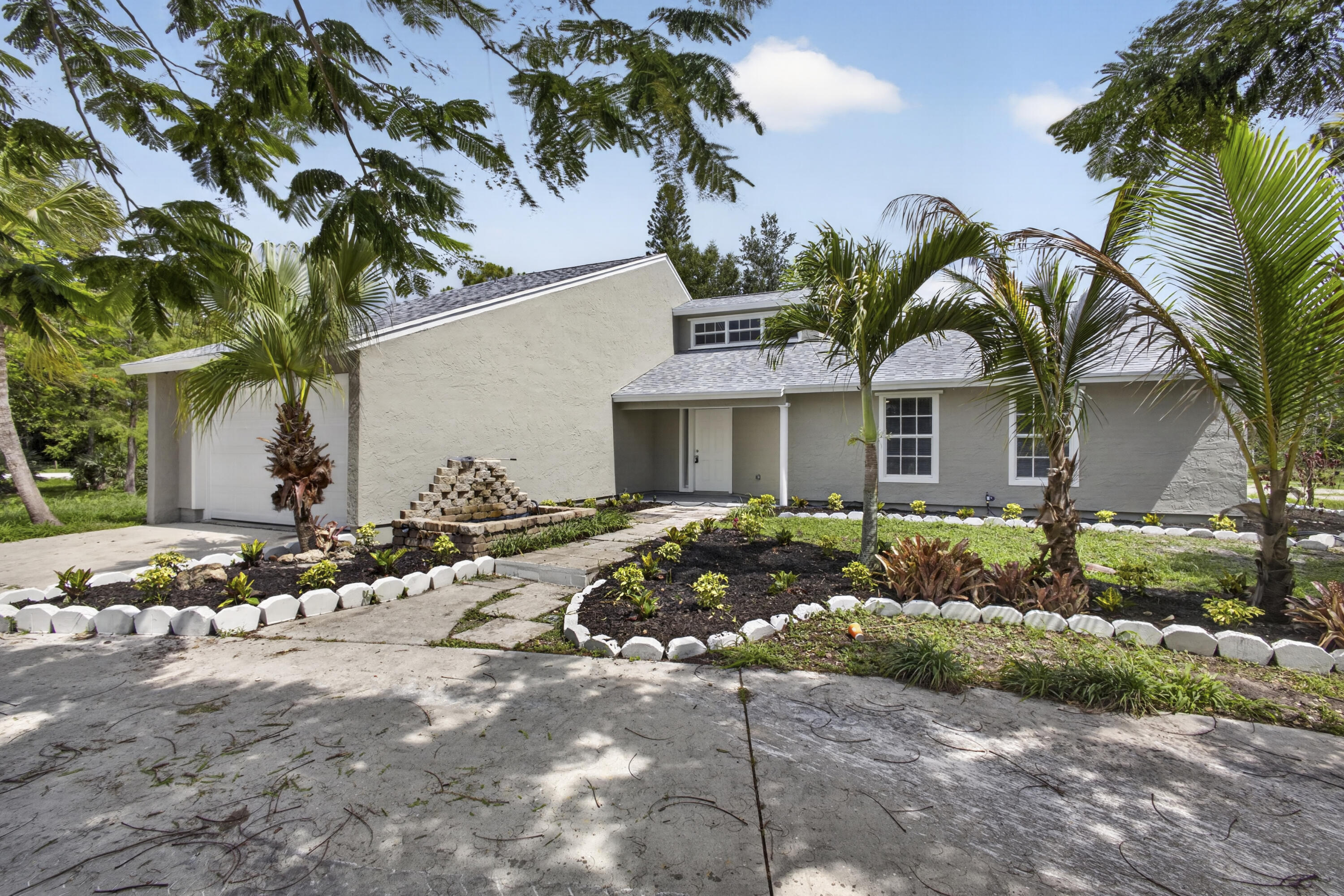 Welcome to the highly sought-after Acreage community in West Palm Beach! Situated on a sprawling 1.25-acre lot with no HOA, this beautifully updated 3-bedroom, 2-bathroom home offers privacy, flexibility, and room to grow. The property features frame/stucco construction, a 2-car garage, public water, new roof, new A/C, new garage door, and a new septic tank. Inside, enjoy an updated kitchen with granite countertops and stainless steel appliances, wood laminate flooring throughout, vaulted ceilings, abundant natural light, and two nicely renovated bathrooms with tiled showers. Relax on the large open patio with endless space for boats, RVs, toys, an addition, or another garage. Call today to schedule your private tour!