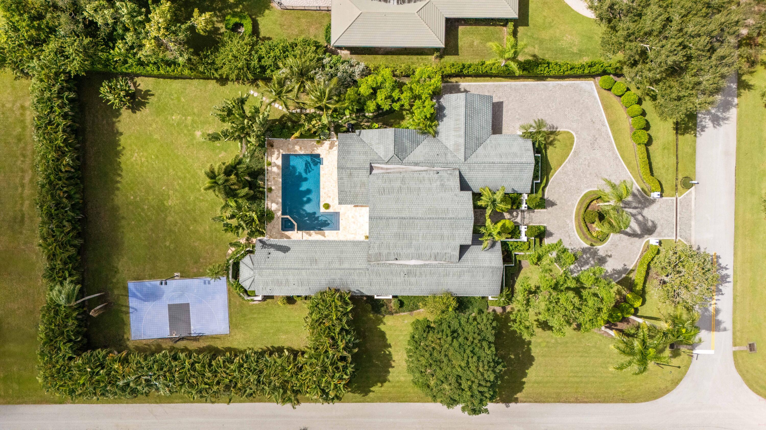 Experience refined Florida living in this fully renovated 1.03 acre single story custom home, totally rebuilt from the inside out. With over 5,000 sq. ft. of living space, this residence offers 4 private bedroom suites, 6 baths, a library-style office with custom built-ins and an upper reading nook, a bonus/game room, and a 4-car split garage.  Perfectly positioned on the corner of the cul-de-sac, the home is surrounded by lush, fully reimagined landscaping that enhances both curb appeal and privacy. The property now features an expansive new decorative circular driveway, designed to allow generous parking and smooth flow for residents and guests. Nearly every major component has been replaced and updated, including the roof, impact windows, electrical, plumbing, 3 AC units, irrigation system, garage flooring, new driveway, and all interior flooring.  Inside, abundant natural light fills the open living spaces, where French doors overlook the newly resurfaced pool and spa. The fully redesigned kitchen features new appliances, custom cabinetry, and sleek quartz countertops.  The spacious Primary Suite offers generous his-and-her custom closets and a spa-inspired bath with peaceful garden views. All guest suites include remodeled ensuite baths. The library office showcases beautiful custom built-ins with a cozy upper nook with more storage space.    The backyard is a resort-style escape, complete with a refinished pool and deck, a covered patio with a new built-in grill/bar, a half-court sports area, a poolside shower bath, and a fully fenced yard ideal for entertaining, kids, and pets.  This rare turnkey residence offers luxury, privacy, exceptional natural light, and abundant storage throughout an extraordinary property not to be missed.