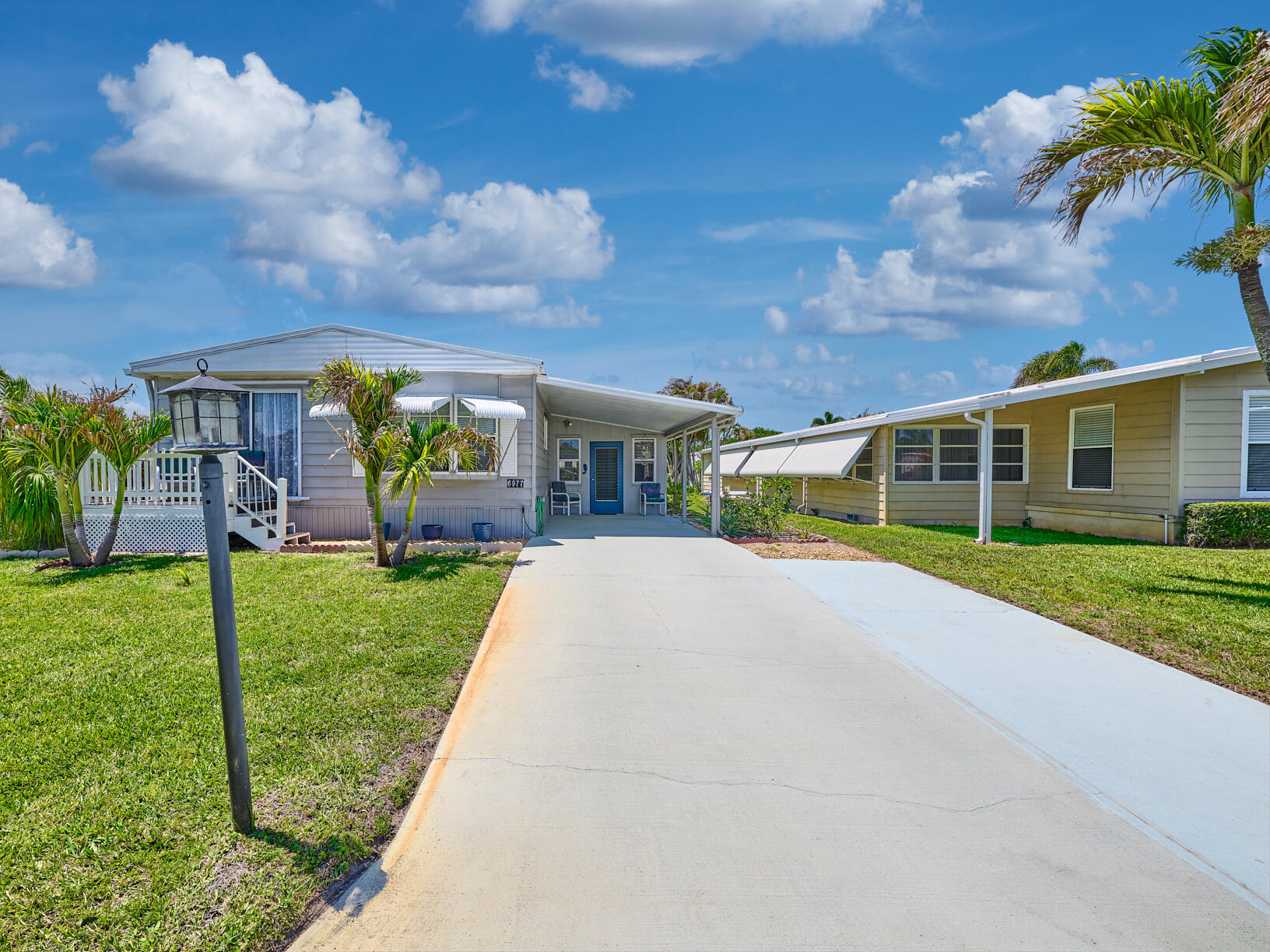 Charming, Seaside Cottage feeling, doublewide in Cambridge, 55 + community in Hobe Sound.  Coastal paint colors throughout! Sunny front porch to enjoy the sunrises & sunsets while having your morning coffee or evening refreshmentsl. The Living Room & Dining Area are light filled w a Bay window & Slider to the outside facing South. The Galley kitchen is so convenient w lots of cabinets. The owners have many Friends visiting so made many different areas to welcome them. The flooring throughout is luxury vinyl planking adding to the beachy feel. The Primary Bedrm spans the entire width of the home w a huge walk in closet, & another bay window & ensuite bath. The 2nd bedrm is a good size w full bath on the hall. New roof 2017, New A/C 2019. YOU OWN THE LAND - ALL PETS WELCOME. LOW HOA