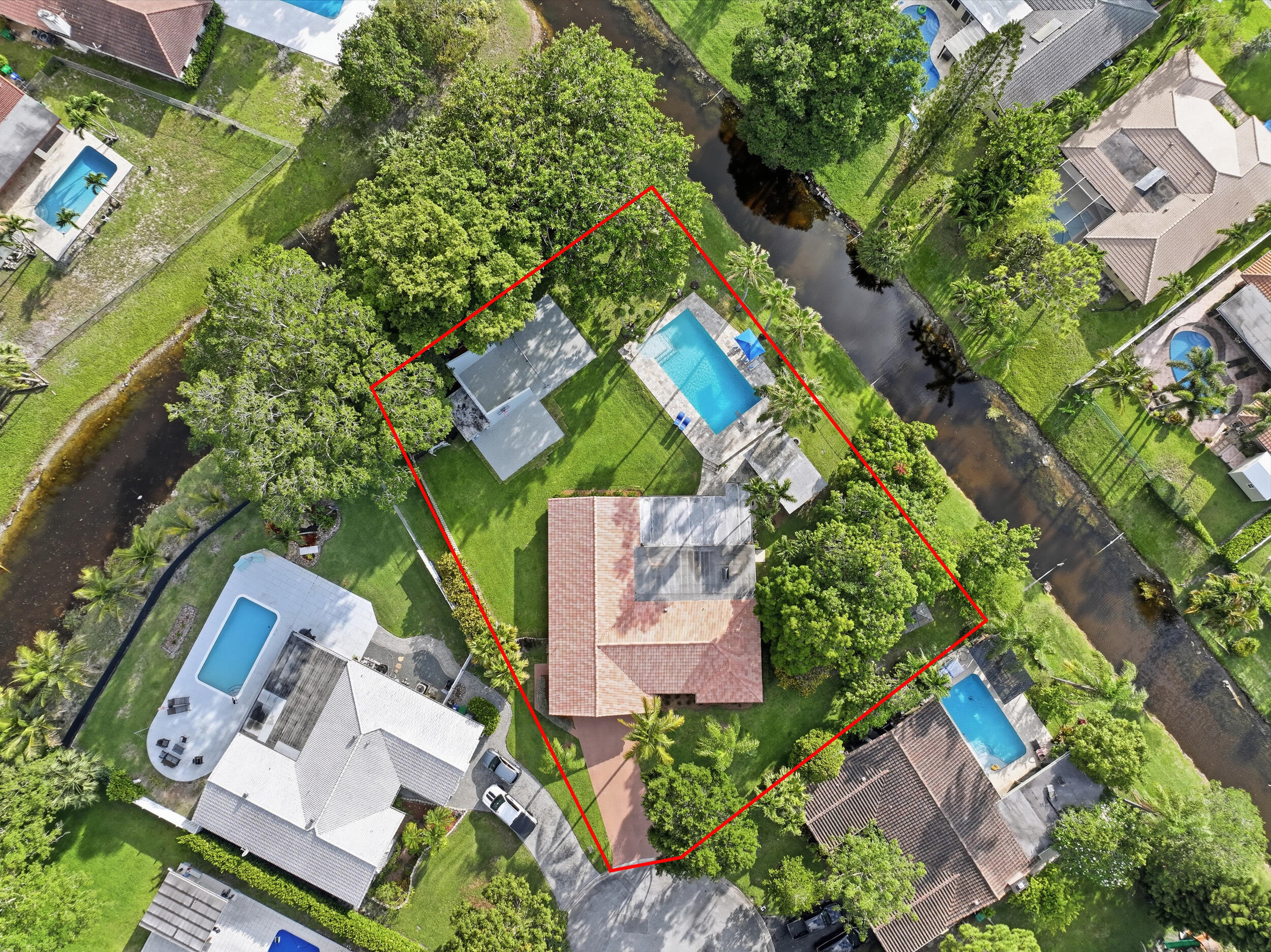 One-of-a-kind property built for those who work from home, need extra space, or run a business. Located on a private cul-de-sac, no HOA, this home sits on a half-acre, 20,881 sq ft lot with 230+ ft of canal frontage , no rear neighbors, offering rare privacy in Coral Springs/Parkland. The 5-bedroom, 3-bathroom home offers 2,779 sq ft of living area, plus a detached office (with mini split a/c), bringing total functional space to 2,912 sq ft. Ideal for a office, studio, gym, or client space. Perfect for sports and entertaining, with a racquetball/pickleball court, half basketball court, and 20' x 40' resort-style pool with diving board, zip line and sun shelf. Chef's kitchen includes a 48" Thermador propane gas range and custom refrigerator/freezer. Plenty of land for an ADU or guest house. Updates and Features: • New Mohawk waterproof laminate in bedrooms, living room and family room.  • Full hurricane protection with all impact-resistant windows and doors (wind mitigation attached) • Epoxy chip pickleball and basketball court - just painted  • New flat roof and skylight (2022)  • Updated electrical panels installed inside and outside  • New Electrical ran to detached office and pool heater. • A/C replaced (2019)  • Concrete tile roof replaced (2006)  • In 2004, the home was expanded (permitted) with the addition of a bedroom, bathroom, pantry, and breakfast area  • New Pool Pump Variable Speed, Jandy Truclear salt cell system, multi color pool light, and electric pool heater • New silver travertine patios and pool deck (over 2400sf)  • Pool remodel, new surface, new waterline tiles, new shelf with bubblers and umbrella.   • Textured walls and ceilings • Updated Fans and Lighting • Kitchen with wood cabinetry, custom full-size fridge and freezer, 48' professional Thermador gas range • Tankless gas water heater  • Solid Core Wood Doors throughout • Updated closet doors • Crown molding • Updated guest bathroom, modern tile flooring, quartz vanity, new commode and new tile shower and glass accent  • Updated guest bathroom, newer tile floor, modern vanity, newer commode and newer glass tile around the tub area. • Detached office or work studio, with mini-split A/C, impact-resistant door, and impact-resistant window  • Large side gate with ample space to store recreational vehicles  • Two detached concrete block storage buildings (approx. 235 sq ft total)  • Oversized two-car garage  • Stamped concrete driveway with parking for approximately six vehicles  • Wood and chain link perimeter fencing • Firepit area