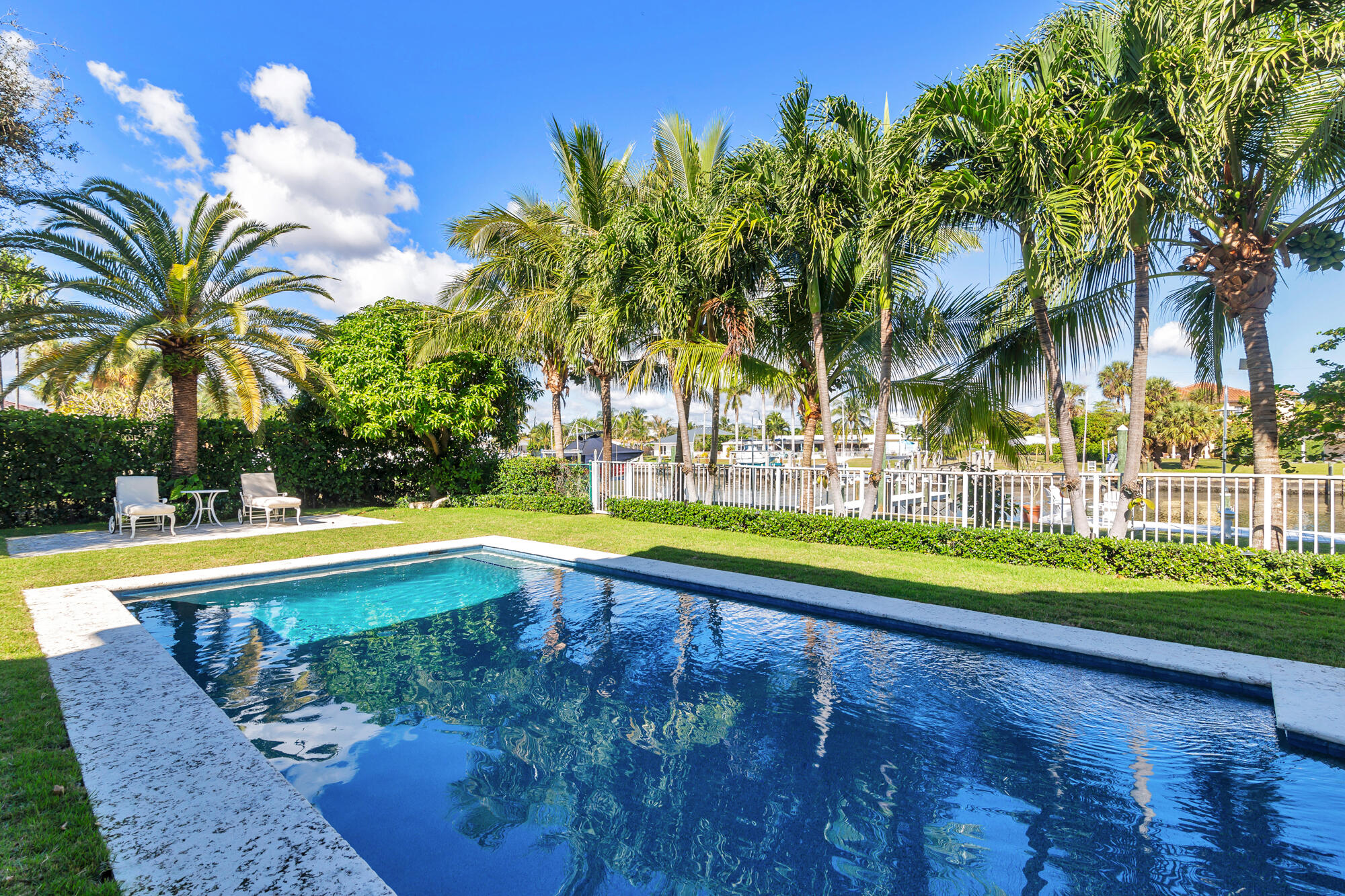 This stunning waterfront property in Lake Worth offers the perfect blend of luxury, privacy, and functionality. Situated at the end of a quiet cul-de-sac, the home boasts 125 feet of water frontage with a private dock, a 13,000-pound boat lift, and serene views from almost every room. Designed for both relaxation and entertaining, the property features a beautifully landscaped yard, a heated saltwater pool, and a covered outdoor loggia. Inside, the light and bright interior spans 4,546 square feet and is thoughtfully designed with seamless indoor-outdoor living in mind. The two-story foyer creates a grand first impression, leading to elegant living and dining rooms that open directly to the pool and waterfront. A large family room with a wet bar connects to the gourmet kitchen, which is perfect for the culinary enthusiast. The kitchen boasts a gas range, Sub-Zero refrigerator, a full Viking wine fridge, a cooled wine closet, and a walk-in pantry. Upstairs, the primary suite is a luxurious retreat featuring two walk-in closets, dual sinks, a soaking tub, a large shower, and a private water closet, all complemented by stunning water views. Two additional upstairs guest suites each include en suite baths and spacious closets. A fourth bedroom, located on the main floor, provides flexibility and convenience. Built for peace of mind, the home is equipped with hurricane impact doors and windows, a thick gauge standing-seam metal roof with straps, and a 24 kW generator. A whole-house water filtration system ensures fresh water throughout, while a security and camera system enhances safety. Full landscape lighting adds to the property's charm, while a two-car garage and extended driveway offer ample parking.