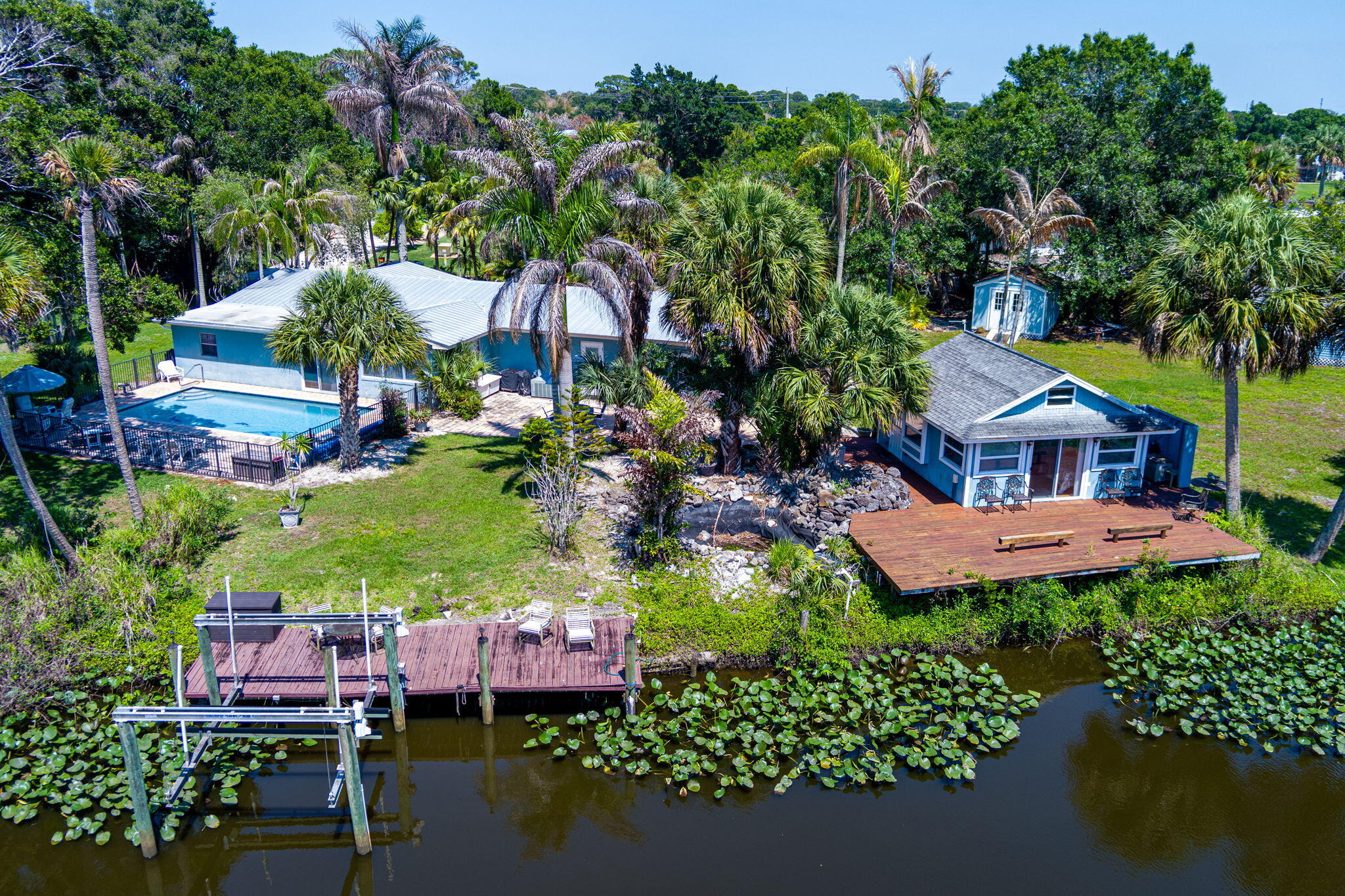 Discover a rare stretch of riverfront living on the North Fork of the St. Lucie River, where over 250 feet of direct waterfront sets the stage for true Old Florida charm. Situated on a sprawling half-acre lot, this unique property offers the kind of privacy, space, and character that's becoming increasingly hard to find. The home features three bedrooms and two baths. living and family room. You will love the custom-designed kitchen, granite counters and gorgeous wood cabinets. Designed for both relaxation and adventure, the property features ocean access, a private boat/kayak launch, and a dock with a boat lift —making it effortless to spend your days on the water. Whether it's sunrise paddleboarding or relaxing by the pool. spending the afternoon fishing or cruising out the inlet, this home delivers the full Florida experience. The main residence is complemented by a separate guest cabana, that is perfect for a creative retreat. Surrounded by mature tropical landscaping and wide water and nature preserve views, the setting feels peaceful and tucked away, yet remains conveniently close to everything Port St. Lucie and Fort Pierce have to offer.  Roof replaced in 2022! Existing sheds can stay and are as-is. Very hard to find property with this much frontage, flexibility, and character -- this is your opportunity to own a true waterfront retreat.