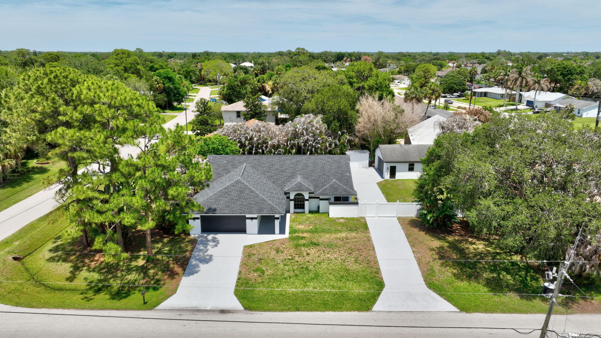 RARE FIND: Double Lot, 0.47 Acre, No HOA, 4-Car Garage Capacity, Dual Driveways for Boat/RV! Welcome to 1721 SW Ocean Cove Avenue in the sought-after community of Hidden Oaks—a move-in-ready contemporary corner lot home that blends modern style with exceptional functionality on nearly half an acre. This spacious 3-bedroom, 2-bath residence offers 2,430 square feet of living space, plus a large flex room ideal for a home office, gym, or media room. From the moment you step inside, you'll appreciate the clean, modern aesthetic highlighted by fresh 2025 interior and exterior paint in crisp white with striking black accents, high-quality laminate flooring throughout with no thresholds, and soaring volume ceilings that enhance the open feel. At the heart of the home is a beautifully updated gourmet kitchen featuring a large island, butcher block countertops, a glass recessed pantry, ducted range hood, and LG dual oven perfect for both everyday living and entertaining. A spacious walk-in pantry and expansive dining area add to the home's thoughtful design. The primary suite is a private retreat, complete with a luxurious en-suite bath offering a dual sink quartz vanity, freestanding soaking tub, oversized walk-in shower, and bidet toilet. Additional features include soft-close cabinetry and pocket doors throughout, recessed LED lighting, a whole-house water filtration system, and a living room prewired for in-wall and in-ceiling speakers. Step outside to enjoy the fully fenced backyard, surrounded by lush tropical landscaping with mature Areca palms and pine trees for added privacy. With nearly half an acre, there's ample room to add a large pool or create your own outdoor oasis. Car enthusiasts, hobbyists, or those needing extra storage will love the rare combination of an attached 2-car garage plus a detached 2-car garage with an 8-foot door—perfect for boats, RVs, or other toys—along with a large utility shed and two expansive driveways for easy access. Major updates include a new roof (2023), AC (2017), and water heater (2026), offering peace of mind for years to come. Conveniently located near shopping, dining, and I-95, this exceptional property offers the perfect blend of modern upgrades, space, and versatility in a prime Port Saint Lucie location. See this unique Port Saint Lucie Gem before it is gone!