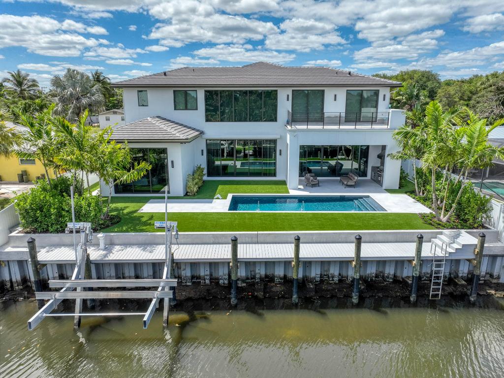 Move in TODAY! Picture yourself indulging in the high-end designer touches and tasteful details that adorn this waterfront haven, free from fixed bridges. This residence offers 5 generously proportioned bedrooms, 5.5 modern bathrooms, and a 3-car garage, ideal for those seeking to savor life on the water to its fullest. The Exterior of the home is designed with new tech UV resistant Belgian board fluted paneling, Eldorado European Ledge stone and Avenue coach lights. Upon entry, the main level captivates with its expansive 30x60 Perla tiled floors and an elegant decorative fireplace cast in Graphite Fabuloso, complemented by custom bar designed by Luis Daniel Salazar Vazquez. The soaring ceilings, dramatic mood lighting, and discreetly integrated hidden doors add to the allure. The gourmet kitchen, outfitted with Sub Zero and Wolf appliances, Mia Cucina Custom Cabinetry, Bianco Supreme quartzite counters, 150 bottle dual controlled wine cooler and a uniquely designed island adorned by Seed pendant lighting sets the stage for culinary excellence.
Concealed behind one of the many discreet hidden doors lies the primary bedroom suite, offering unobstructed pool and water vistas, a lavish spa shower, Kasa Panelli matte light walls and meticulously crafted custom closets. Missoni, Arte and York Wallpaper throughout the home adds to the Luxe feel. Ascend the striking, light-filled staircase with custom metal powder coated railing to discover a loft and children's playroom, an additional laundry room, and bedrooms each boasting en-suite bathrooms. Step onto the expansive balcony upstairs and bask in the breathtaking sunrise views. Designed for outdoor entertaining, the living area seamlessly transitions to a sprawling covered patio equipped with phantom screens, pool deck with 24 x 48 porcelain tiles, capri stucco gem finished pool and a summer kitchen set in floor to ceiling Dekton Keon. Enjoy the convenience of a brand-new boatlift, dock with water and electric pedestal and 16k lift, new poured retaining wall on Seawall, along with a verdant turf backyard and meticulously manicured landscaping. For those in search of a home that effortlessly blends luxury with comfort, look no further. This residence stands as a testament to refined living, offering a masterpiece of sophisticated design and unparalleled elegance.