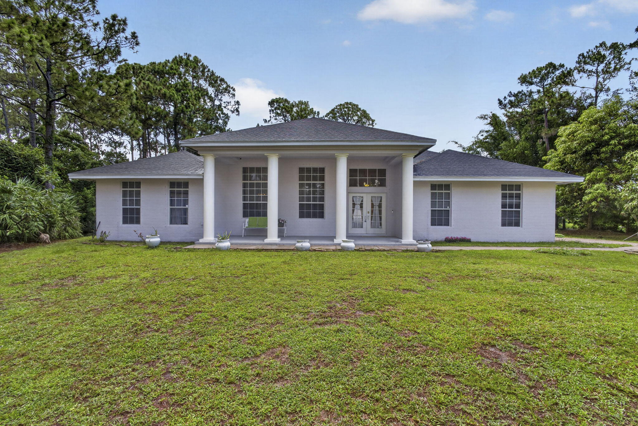 Welcome to this spacious single-story residence in The Acreage, FL, offering 2,572 square feet of comfortable living space. This four-bedroom, two-and-a-half-bath home provides ample room for versatile living arrangements and entertaining. The five-car garage offers exceptional storage and parking capacity for multiple vehicles or additional space for hobbies and projects. Located in the Acreage subdivision, this single-family residence combines practical layout with generous square footage to meet diverse lifestyle needs. Whether you're seeking a primary residence or investment opportunity, this property delivers functionality and space in an established community setting. Grand entrance living and dining area, eat in kitchen, large family room, split bedroom plan with oversized rooms. grand master bath. Detached 3 door  building 30 x 30 plus attached 2 car garage. Large newly screened patio with multiple potted orchids. Quiet paved dead end street.  Lot is high and dry with 2 haas avocado,2 lychee, and multiple mango trees, the perimeter is Florida natural foliage on 2 sides beautifully manicured. West side of the property nicely shaded from the trees to help cool the home.The backyard has a small butterfly garden with lawn chairs and umbrella waiting for you to relax this summer. Brand new water heater, home was just painted along with a mold resistant undercoat, back patio complete with all new screens. lawn mower, leaf blower, high pressure water blaster, 40 watt weed eater, various garden tools, along with 2 industrial sized fans all convey, full exterior camera coverage with the ability to lock and unlock house remotely. New roof approximately 7 years ago. For those with pet allergies, no pets have ever been in the home.