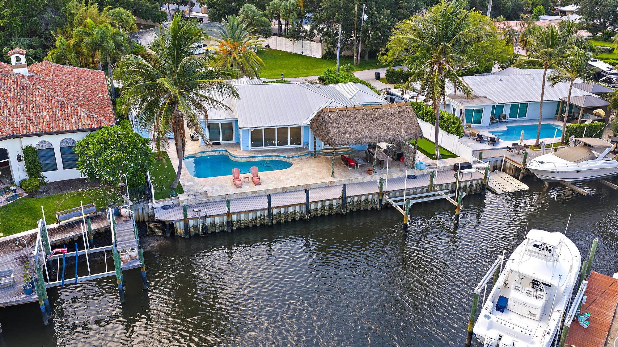 This property presents a rare opportunity to enjoy privacy, flexibility, and the South Florida lifestyle. A generous lot size with ample room for outdoor living, expansion, or customization to suit your needs. Set along the water with access to the Intracoastal, the property offers 103' of water frontage, 98' of Trex Dock, and a 12,000lb lift ideal for enjoying boating and the surrounding coastal lifestyle. The residence features a functional layout with abundant natural light, comfortable living spaces, and seamless indoor-outdoor flow. Impact windows and doors throughout. Enjoy the convenience of being just minutes from shopping, dining, golf courses, and some of the area's most desirable amenities, while still maintaining a sense of seclusion and tranquility.