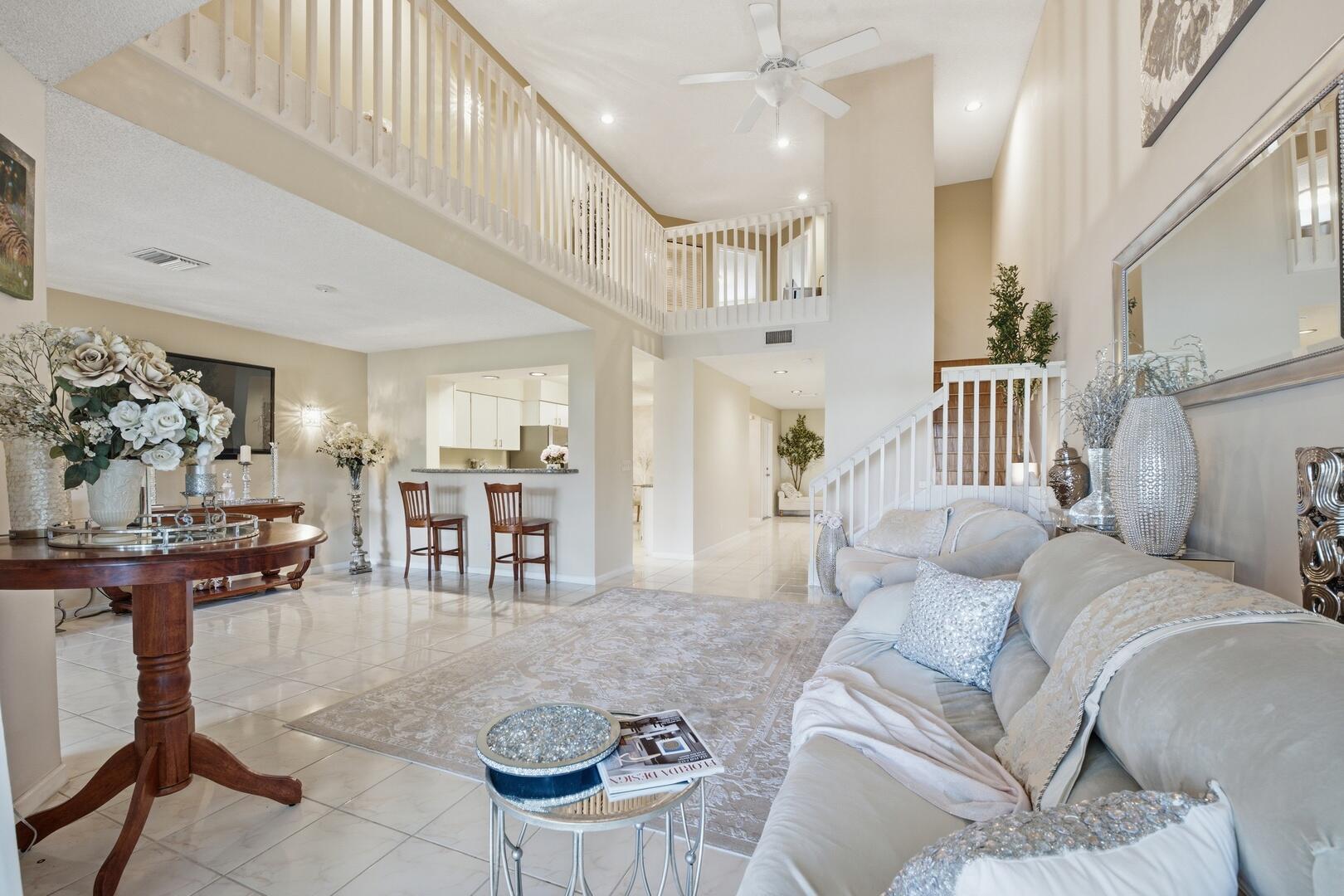 Welcome to one of the most exceptional residences in Boca Gardens, offering the largest floor plan in the community, breathtaking lake and fountain views, and a rare blend of architectural volume, natural light, luxury upgrades, and prime West Boca Raton convenience. This beautifully maintained 3-bedroom, 2.5-bathroom townhome immediately impresses with soaring 17-foot ceilings, dramatic open living spaces, and an abundance of natural light pouring through oversized windows. The expansive two-story living room creates a true sense of elegance and grandeur, while the upstairs loft overlooks the main level, adding both architectural character and versatile living space.  Designed with both comfort and sophistication in mind, the home features smooth walls, neutral contemporary finishes, ceramic tile throughout the main living areas, newer flooring in all bedrooms, rich hardwood stair accents, and refined lighting fixtures throughout. Every space has been thoughtfully curated to create an airy, luxurious atmosphere.  The gourmet kitchen offers granite countertops, Maytag stainless steel appliances, abundant cabinetry, and a bright eat-in breakfast area. Flowing seamlessly into the formal dining area and spacious living room, the layout is ideal for both entertaining and everyday living. A versatile first-floor den or study with tranquil water views provides the perfect space for a home office, library, media room, or private guest retreat. The space also offers the flexibility to be converted into an additional first-floor bedroom, ideal for multigenerational living, guests, or added convenience and functionality.  Upstairs, the oversized primary suite serves as a private retreat, featuring panoramic lake views, elegant high-hat lighting, a large walk-in closet, dual vanities, and a spacious walk-in shower with glass doors. Two additional generously sized guest bedrooms — each large enough to accommodate king-size furniture — also enjoy beautiful water views and share a well-appointed bathroom with dual sinks and a shower/tub combination.  Step outside to the screened and covered patio, beautifully finished with tile flooring and overlooking serene lake and fountain views. Whether enjoying your morning coffee, entertaining guests, or relaxing at sunset, this outdoor space captures the very essence of South Florida living.  Major upgrades provide exceptional peace of mind, including: • New Roof (2024 - maintained and replaced by HOA) • New AC System (2025) • New Water Heater  Ideally positioned within walking distance to the east pool, Publix, bagel shops, restaurants, banks, and everyday conveniences, this home offers an unmatched lifestyle opportunity in one of Boca Raton's most desirable locations.  Boca Gardens residents enjoy access to outstanding resort-style amenities including: • Three Swimming Pools • Clubhouse • Fitness Center • Tennis Courts • Pickleball • Racquetball • Basketball Courts • Scenic Walking Trails • Five Picturesque Lakes  Conveniently located near top-rated schools, premier shopping, dining, beaches, parks, golf courses, and major highways, this residence offers the perfect combination of luxury, lifestyle, and location.  HOA includes cable, lawn care, exterior painting, common area maintenance, roof maintenance, and roof replacement.  Property Highlights: • Largest Floor Plan in Boca Gardens • 3 Bedrooms | 2.5 Bathrooms • Loft + First Floor Den/Study • Optional First-Floor Bedroom Conversion • Soaring 17-Foot Ceilings • Stunning Lake & Fountain Views • Exceptional Natural Light • Smooth Wall Finish Throughout • Granite Kitchen with Stainless Appliances • Oversized Primary Suite with Water Views • Walk-In Closet + Dual Vanities • Screened Covered Patio • New Roof, AC & Water Heater • Walking Distance to Pool, Shopping & Dining • Prime West Boca Raton Location