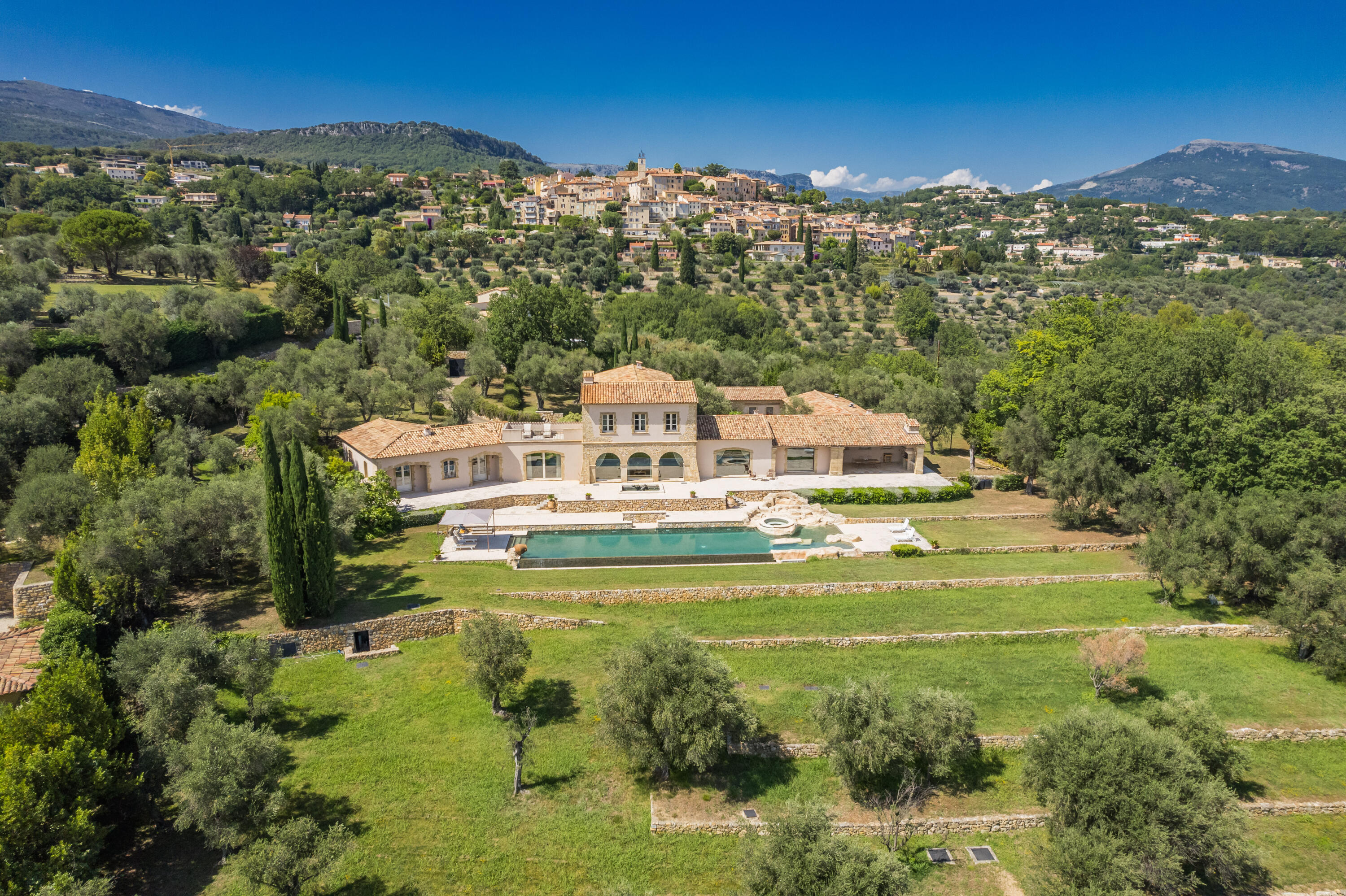 Perched among ancient olive groves just below the charming medieval village of Châteauneuf-de-Grasse, Cote D'Azur. Villa Douce Revanche is an exceptional French Riviera estate offering timeless elegance, privacy, and breathtaking panoramic views stretching across the Mediterranean Sea, rolling countryside, and historic village skyline. Situated on approximately 2.44 acres of beautifully landscaped grounds, this magnificent bastide-style residence encompasses approximately 7,535 square feet of refined living space. The home seamlessly blends classic Provençal architecture with luxurious modern comforts, creating an extraordinary retreat in one of the South of France's most coveted locations. A grand entrance hall welcomes guests into expansive living and entertaining  spaces featuring stone fireplaces, elegant reception rooms, a formal dining area, and a fully equipped gourmet kitchen with breakfast area. Large doors open to covered terraces, creating effortless indoor-outdoor living and entertaining opportunities while capturing spectacular views throughout the property. The residence offers five luxurious bedroom suites, including a lavish primary suite complete with dual dressing rooms, a spacious spa-inspired bathroom, and a private terrace overlooking the surrounding landscape. Additional guest accommodations provide comfort and privacy for family and visitors alike. Designed for both relaxation and entertaining, the estate features a remarkable 79 feet  heated infinity pool with Jacuzzi, expansive stone terraces, summer kitchen, a wine cellar, games room, caretaker's residence, extensive storage areas, and a triple garage. Located approximately 20 minutes from Cannes, world-renowned beaches, luxury shopping, fine dining, golf courses, and private aviation facilities.  The Villa offers an extraordinary opportunity to own a private estate in the heart of the French Riviera while enjoying easy access to the region's most desirable destinations. A rare offering combining exceptional quality, iconic views, and an unparalleled Provençal lifestyle.