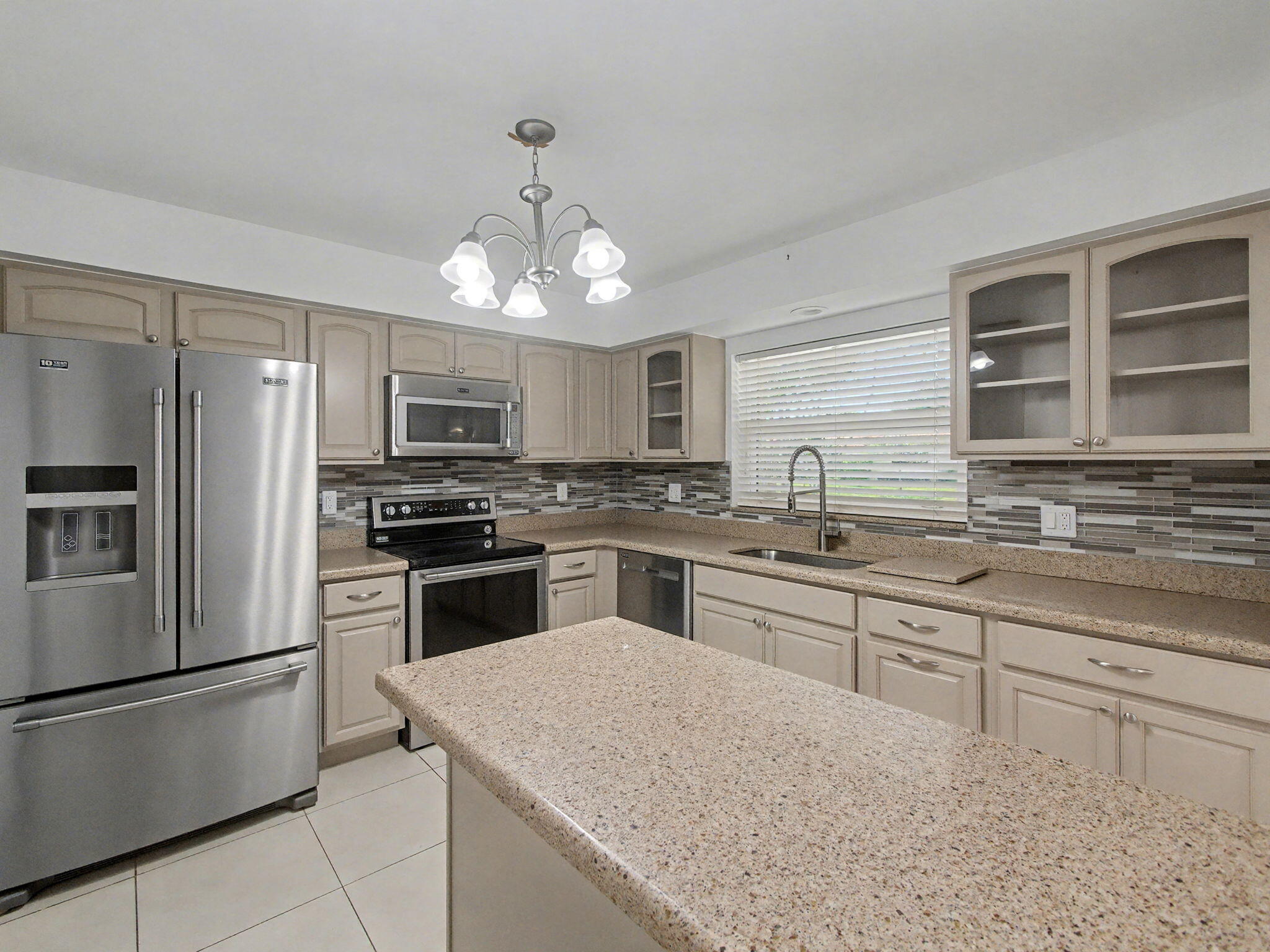 Rare find in Bent Tree Villas West — this fully updated 2-bed, 2-bath villa is the one buyers have been waiting for. From the moment you walk in, it's obvious this home was cared for at a different level than what typically comes to market. Every detail has been touched: new interior doors throughout, updated flooring, fresh ceiling fixtures and fans in every room, and a kitchen that was done right — updated cabinetry, stainless appliances, and the kind of finish that makes you want to cook in it.  The open-concept layout flows through 1,587 square feet of bright, comfortable living space, anchored by a sun room with floor-to-ceiling sliders that open to a private backyard — fully enclosed for privacy, with no rear neighbors. Just green space and quiet, a genuine rarity in this community. The garage surprises you: finished tile flooring, custom shelving, and real organized storage that most units simply don't have. All of this inside one of Boynton Beach's most sought-after 55+ gated communities. Bent Tree Villas West offers resort-style amenities — pool, clubhouse, beautifully maintained grounds — and an HOA that covers water, sewer, cable, and insurance at $559/month. Flood Zone X means no flood insurance required. Twenty minutes to the beach. Thirty minutes to both downtown Boca Raton and downtown West Palm Beach. Homes priced right here sell in under three months — and this one is priced right. Turnkey doesn't get more turnkey than this.