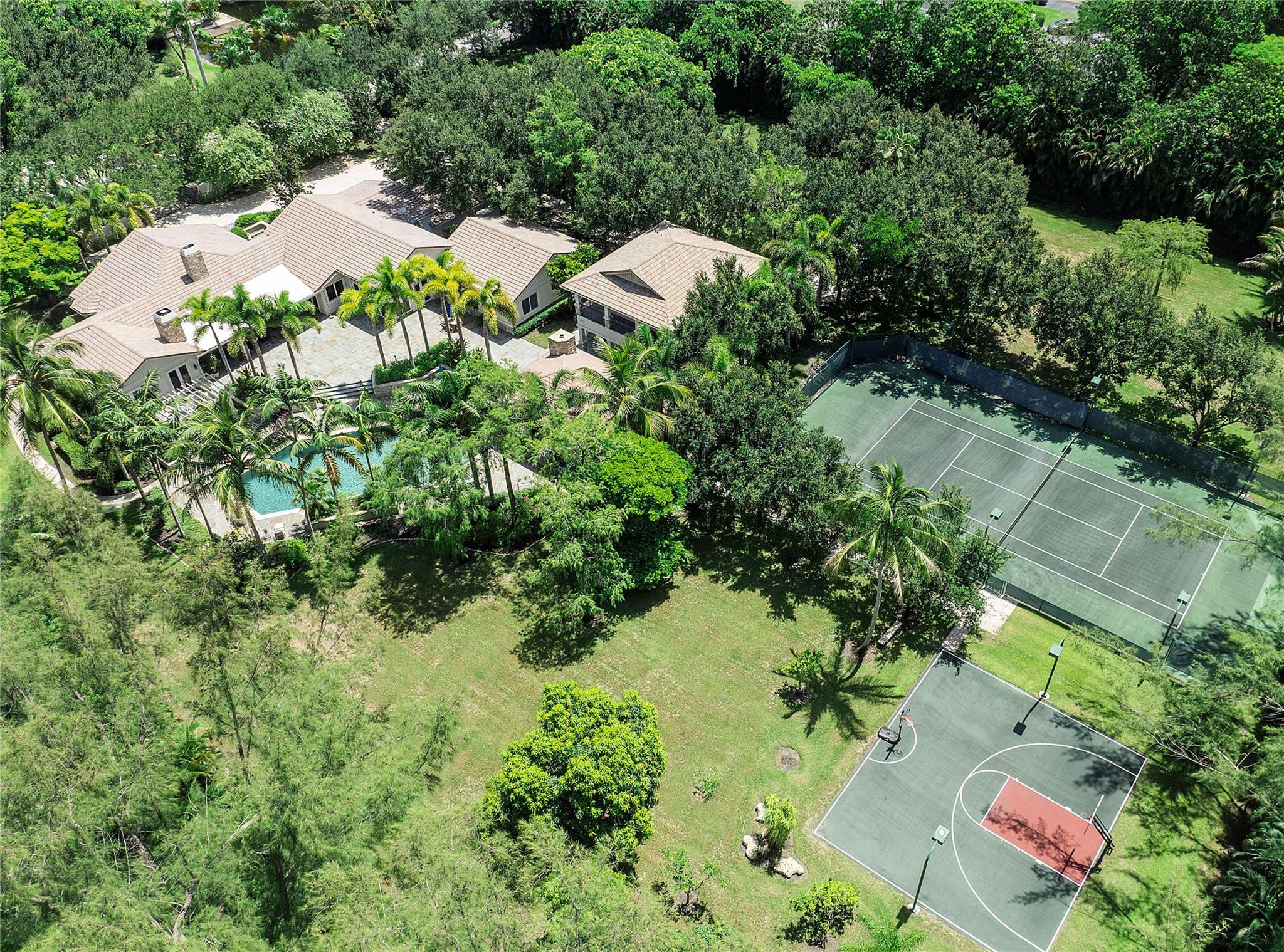 Total perfection in this one-of-a-kind Private Estate in Parkland! Main house w/ 6 bedrooms + office + den & 7 baths. Guest House w/ 3 bedrooms & 2 baths. All located on 3 beautiful acres of landscaped luxury! The ultimate family resort w/ lighted tennis court, basketball court & huge open field to play. Amazing covered gazebo w/ two grills, fireplace, TV & view of hotel-style pool & hot tub!  Gorgeous custom kitchen w/ premium Wolf & Sub-Zero appliances, 2 dishwashers, 2 ovens, 2 wine coolers, built-in Miele & much more! Built in 2009 w/ elegant finishes, stunning millwork, impact windows & doors, wood beams & floors. Property has mango trees, lime trees, banana trees -  enjoy your own tropical oasis in the exclusive Ranches! Whole home generator, plenty of room for stables. No HOA.