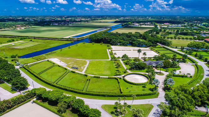 A RARE OPPORTUNITY to own location, acreage, and an income producing property!! Situated on 12.27 beautifully manicured acres, The Ridge is perfectly located in Wellington's highly sought after Palm Beach Point East. The main barn features 14 matted stalls, office, tack and feed rooms, outdoor wash racks, 2bd/1Ba  apartment with separate entrance, an efficiency apartment and 2 laundry rooms. Enjoy riding in either of the 2 sand rings or on the oversized Grand Prix Field. Lining the outer edge of the property are 7 large irrigated grass paddocks, 80' round pen and 3 separate gated entrances off the paved road of Palm Beach Point Blvd. The Ridge is Just a short hack to the recently opened back gate of the 
Wellington International show grounds.