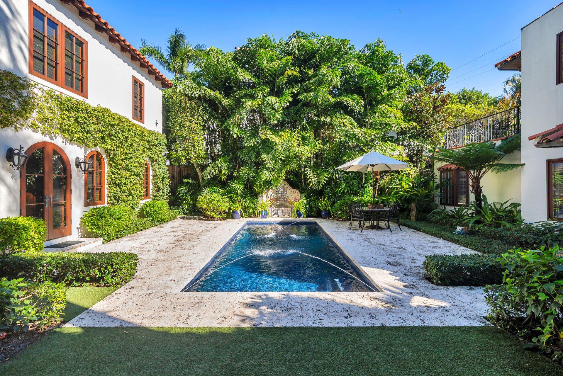 "Tradewinds" - Palm Beach In-Town Private Retreat! Tradewinds is a rare jewel on one of the island's most coveted in-town streets. Originally designed by celebrated architect Maurice Fatio, this masterfully restored 5-bedroom, 5.5-bath compound seamlessly marries historic grandeur with every modern luxury. Set on an exceptional 171-foot-deep lot, the lushly landscaped grounds unfold around three private coquina stone courtyards -- creating a serene, resort-like flow ideal for both intimate living and elegant entertaining. A sun-drenched heated pool anchors the outdoor living space, framed by mature tropical plantings that ensure total privacy. Inside the main residence, soaring vaulted ceilings clad in signature pecky cypress define the dramatic main salon, with a gas fireplace, original stone floors, and a handcrafted Herpel mantle pay homage to Fatio's timeless vision. An arched entry foyer sets the tone upon arrival, leading seamlessly through beautifully appointed principal rooms finished with Hartman impact doors and windows throughout. The primary suite and two guest suites are housed in the main home, while a fully independent two-story guest house offers two additional suites, a private kitchenette, open-concept living and dining, and a south-facing sun deck -- perfect for hosting family or overflow guests in complete comfort. Situated just a half-block from the new Town Docks and a short walk from Worth Avenue's world-class shopping and dining, this is quintessential in-town Palm Beach living at its most refined.   Sold partially furnished.