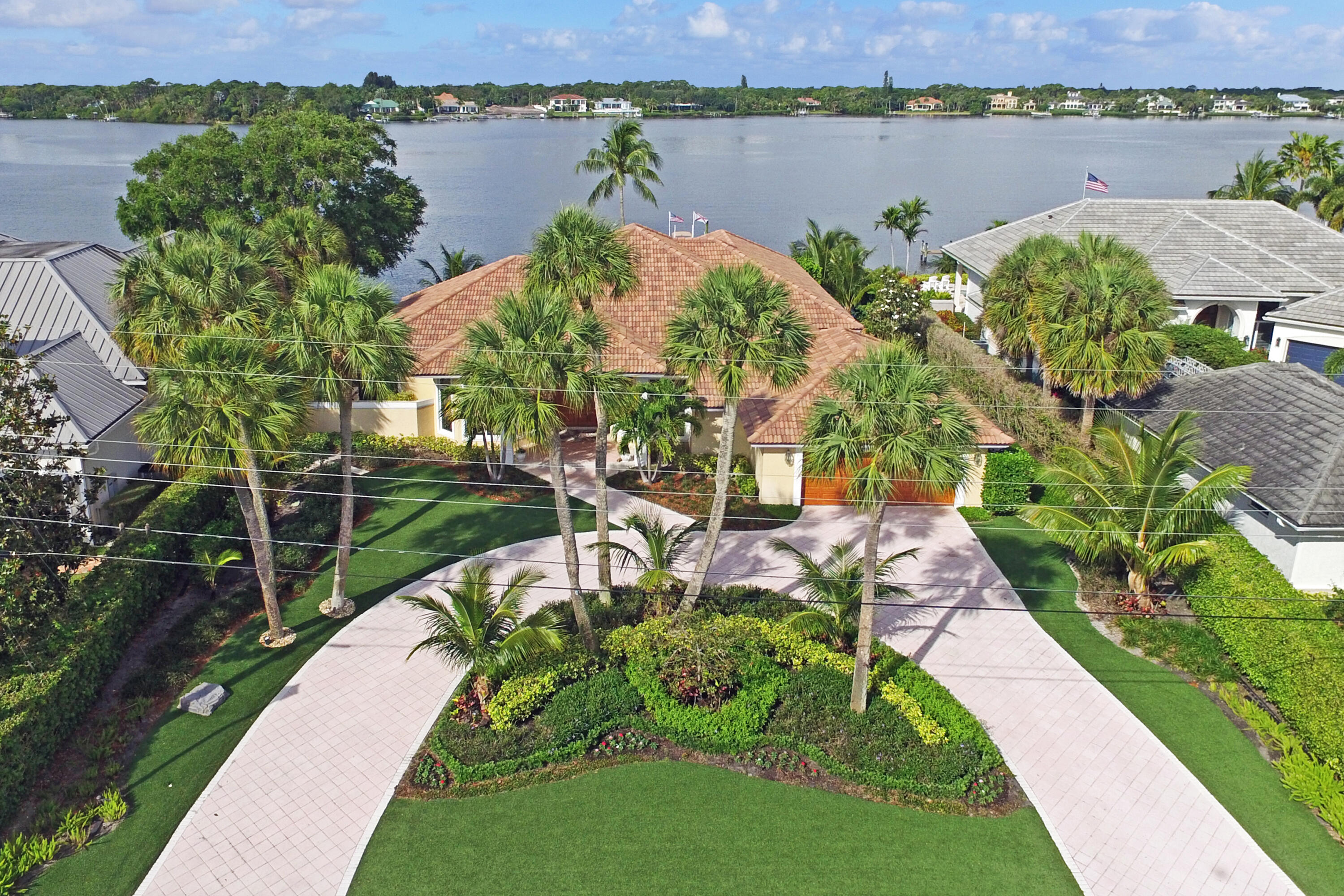 The House of Light...  This custom, waterfront Neandross Estate Home boasts 180°, half-mile views of the glistening Loxahatchee River and breath-taking sunsets embrace the full advantage of the highest elevation on one of the widest parts of the river.  Situated on over half an acre, this property includes 108' of river frontage and has a newer extra-wide sea wall, private dock, deep water dockage, 35K boat lift, sand beach, free-form pool, and dockside cooking deck. The partially covered, screened-in back patio stretches the full length of the house and features a heated spa and built-in grill. The front and back of the house are landscaped with maintenance-free synthetic grass.