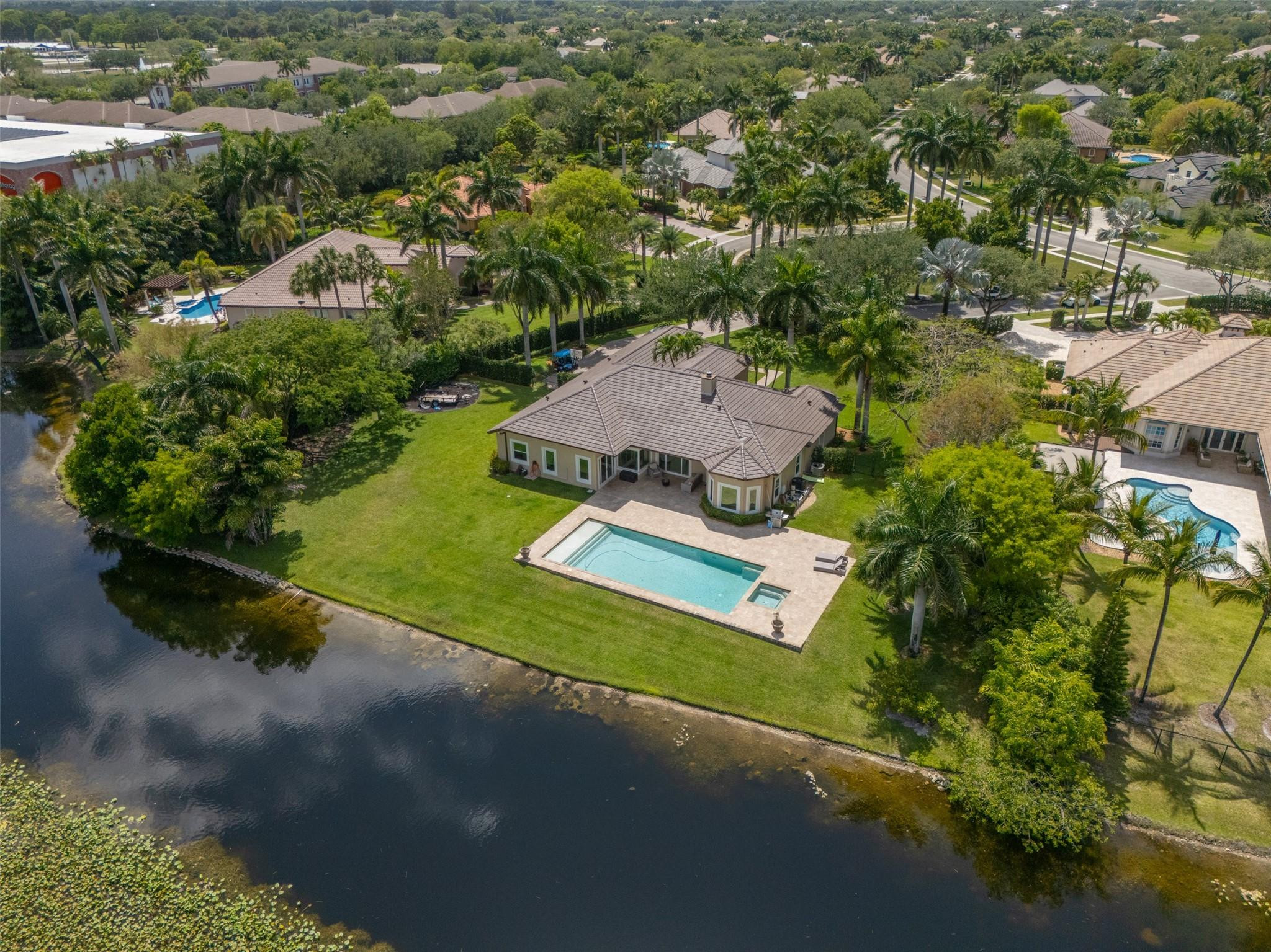 Nestled in the gated community of Grove Creek, this home sits on a quiet cul-de-sac, on a builders acre, offering ultimate privacy & 185 ft wide of gorgeous lakefront views. A long, &wide paved driveway leads to this secluded haven, surrounded by lush hedges for an exclusive feel. Customized enhancements & features including a Brand New kitchen w/ waterfall island,   NEW ROOF, 45x20 heated pool and Jacuzzi, SIW impact & casement windows, (&doors) custom BORANO mahogany wood entry doors, wood-burning fireplace, & 24x24 imported marble flooring and so much more (see list attached). This family- friendly neighborhood offers Western charm, equestrian culture, & natural beauty, close to top-rated schools, highways, shopping, dining, nature trails, horseback riding and more