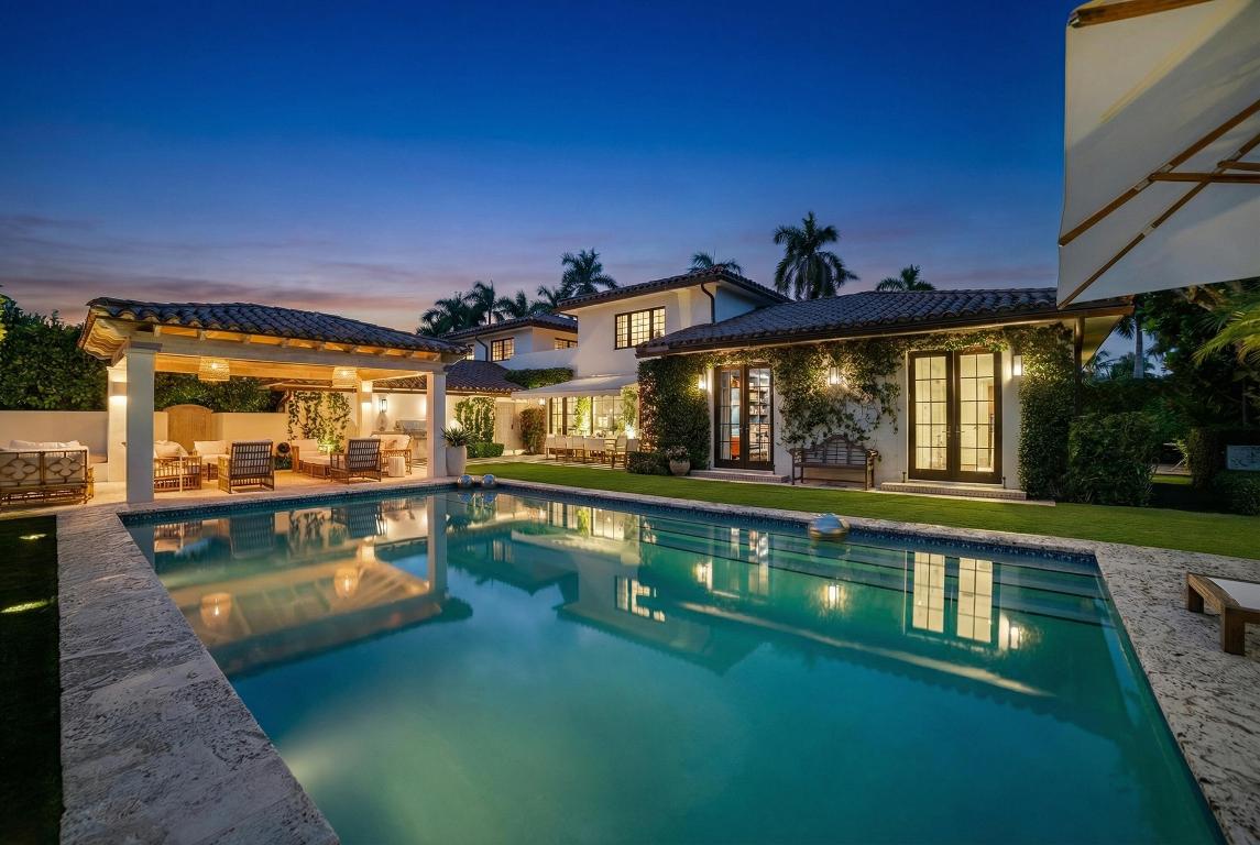 Located in Palm Beach's desirable North End, this Monterey-style residence is set on an oversized 121' x 105' lot and offers 6,138± total square feet with four bedrooms and four and a half bathrooms. The property features exceptional outdoor space, including a generous front yard, a large south-facing pool with terrace, loggia, summer kitchen, and a service entry with a two-car garage accessed from Via Marila.

The foyer, finished with Versailles wood flooring, includes a powder room and introduces the main living areas, with a staircase leading to the second floor. The living room features a gas-burning fireplace, while the formal dining room is filled with natural light and connects directly to the kitchen. The eat-in kitchen is well appointed with a large island, extensive storage, two Sub-Zero refrigerators and freezers, refrigerator drawers, a wine refrigerator, ice maker, a Wolf gas range and double ovens, and dual dishwashers. Adjacent to the kitchen is a laundry room with dual washers and dryers, ample storage, and access to both the side yard and garage.

The spacious family room faces south and opens to the pool and loggia through large windows and doors. A library with custom built-in shelving and cabinetry also provides access to the pool terrace. The first-floor primary suite offers multiple closets and opens to a private terrace, with a bath featuring a steam shower, separate soaking tub, dual sinks, vanity, water closet, and direct access to the pool area.

Upstairs, a terrace overlooks the pool, and three guest bedrooms each feature en suite baths and closets. One guest suite includes dual walk-in closets, dual sinks, a separate tub and shower, and a water closet with bidet.

Other features include whole house water filtration system, fully integrated Sonos system, Tesla charger, tree house, and outdoor shower. Ideally located near the beach and the Lake Trail.