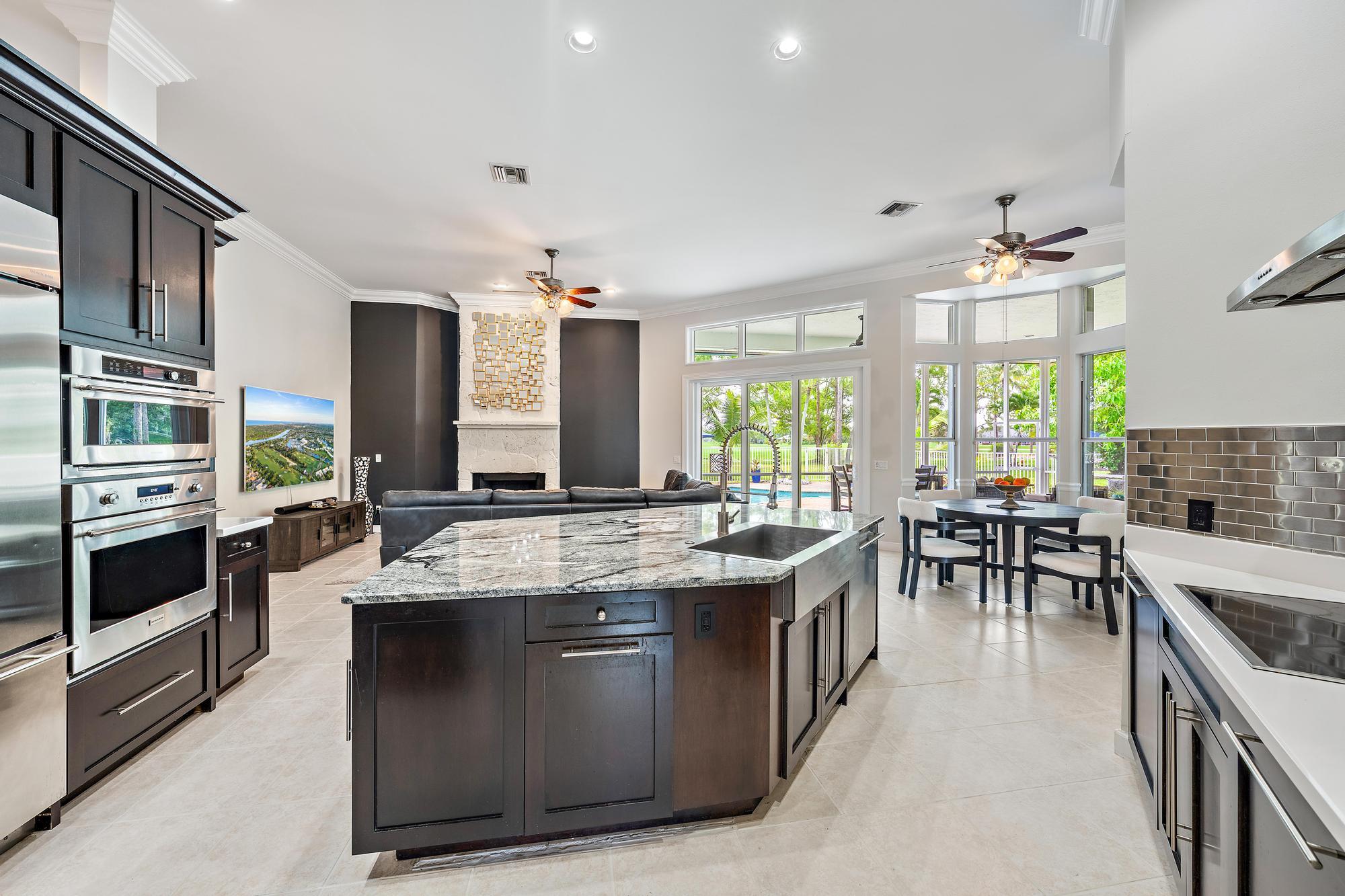 Set on a beautiful one-acre waterfront homesite within the prestigious gated community of Bay Hill Estates, this extensively updated single-story residence combines contemporary and transitional design elements with exceptional space, flexibility, and privacy. Thoughtfully renovated and impeccably maintained, this move-in-perfect 5-bedroom, 4.5-bath home offers more than 4,100 square feet of living space and a rare feature seldom found in the marketplace: a true private mother-in-law suite complete with its own full kitchen, laundry area, living room, dining area, bedroom, full bath, and private patio—ideal for multi-generational living, long-term guests, live-in assistance, or an exceptional private retreat. Designed for both comfort and entertaining, the home's interiors showcase sleek  tile flooring, rich ¾-inch cherry hardwood flooring, extensive crown molding, and elegant dark wood cabinetry that create a sophisticated yet welcoming atmosphere. Contemporary updates and timeless finishes blend seamlessly throughout, while the spacious primary suite serves as a luxurious retreat highlighted by a beautifully renovated spa-inspired bath with exquisite finishes.  Significant infrastructure improvements provide peace of mind, including a roof replaced in 2019, two HVAC systems replaced in 2022, and a new fan motor installed in 2024 for the third system serving the primary suite. The thoughtful maintenance and ongoing enhancements allow the next owner to move in and immediately begin enjoying the home and lifestyle.  The generous floor plan flows effortlessly to the outdoor living areas, where tranquil waterfront views create a picturesque backdrop for relaxing, entertaining, and enjoying South Florida's year-round sunshine. A spacious three-car garage further enhances the home's functionality and convenience.  Located within Bay Hill Estates, one of Palm Beach Gardens' most sought-after gated communities, residents enjoy oversized estate homesites, 24-hour manned security, scenic lakes and canals, walking paths, and optional memberships to the renowned PGA National golf and tennis facilities. World-class shopping, dining, entertainment, and Palm Beach County's pristine beaches are all just minutes away.  Offering a rare combination of one-acre waterfront living, contemporary updates, flexible accommodations, and estate-style privacy, this exceptional residence presents an outstanding opportunity to enjoy one of Palm Beach Gardens' most desirable lifestyles.