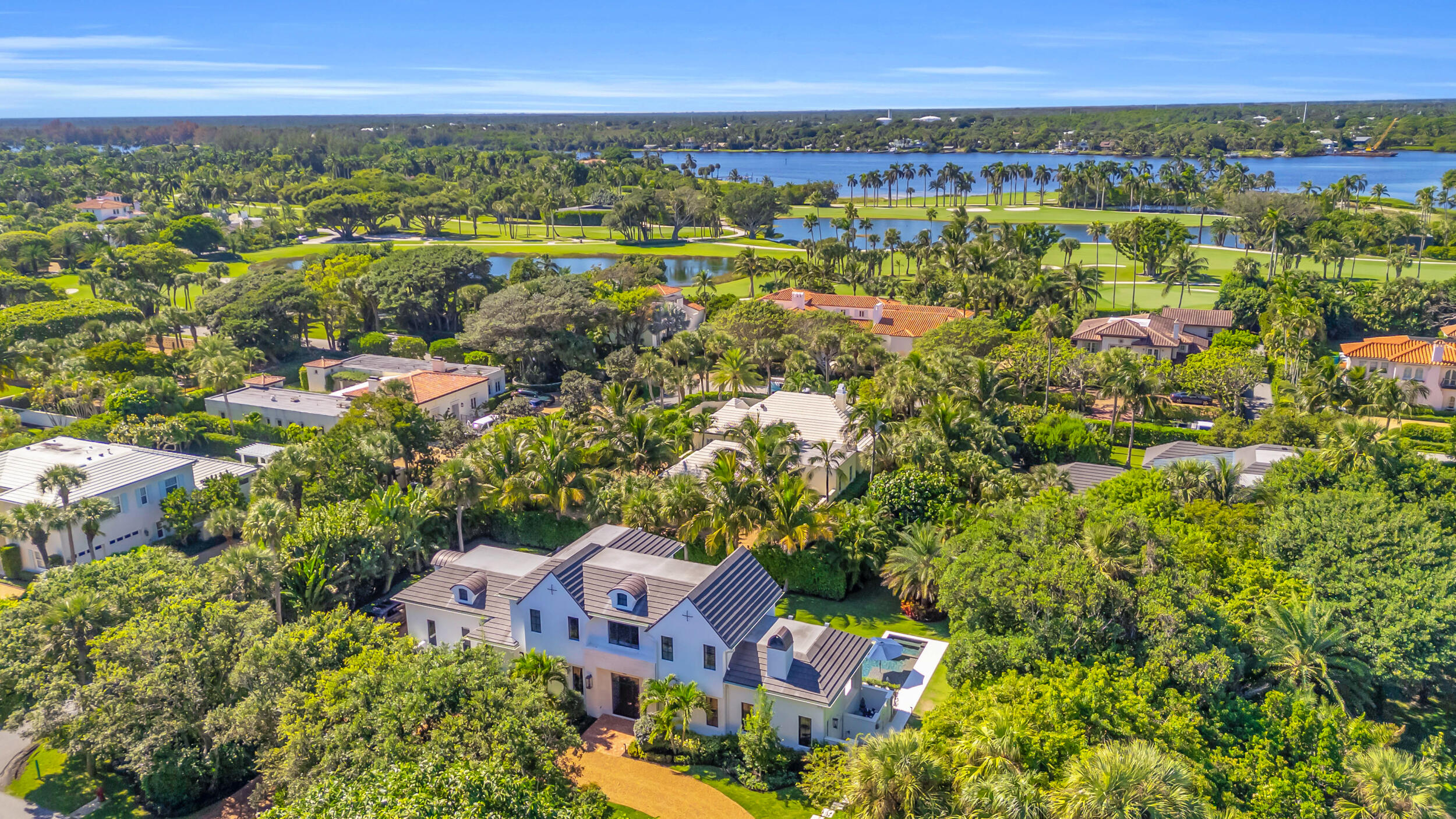 Located near the Jupiter Island Club and Golf Course, this 2023 British West Indies-inspired residence combines timeless architecture with modern coastal luxury. The main level features a gourmet kitchen, spacious living room with gas fireplace, dining area, private office, and a guest bedroom with ensuite bath. Upstairs, the owner's suite offers two custom walk-in closets, balcony access, dual vanities, a walk-in glass shower, and a coffee bar. Two additional bedrooms share a luxurious connecting bath and open to an expansive balcony overlooking the pool. Perfect for entertaining, the outdoor spaces include a covered lanai with summer kitchen and gas fireplace, poolside dining patio outdoor shower, and a heated pool and spa with sun shelf. Highlights: impact-rated windows and doors, whole-home generator, propane gas system, landscape lighting, dual-zone AC, tankless water heater and DEEDED BEACH ACCESS.  Enjoy refined island living just steps from Jupiter Island's private club, golf course, and pristine beaches.